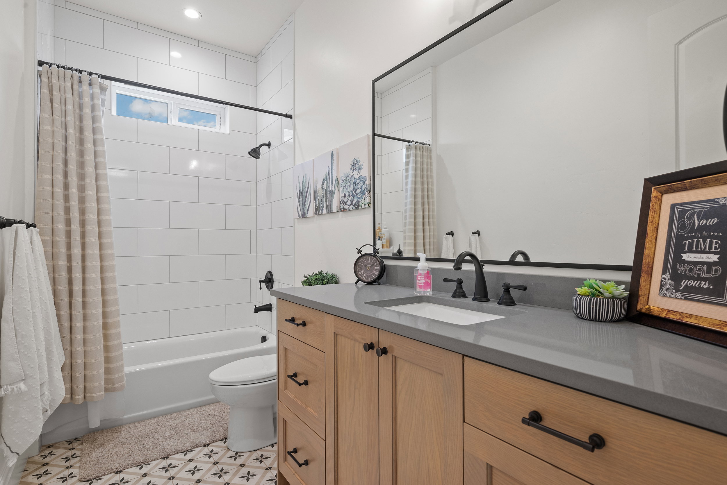 Modern bathroom featuring a single vanity with wood-finish cabinetry and a gray countertop