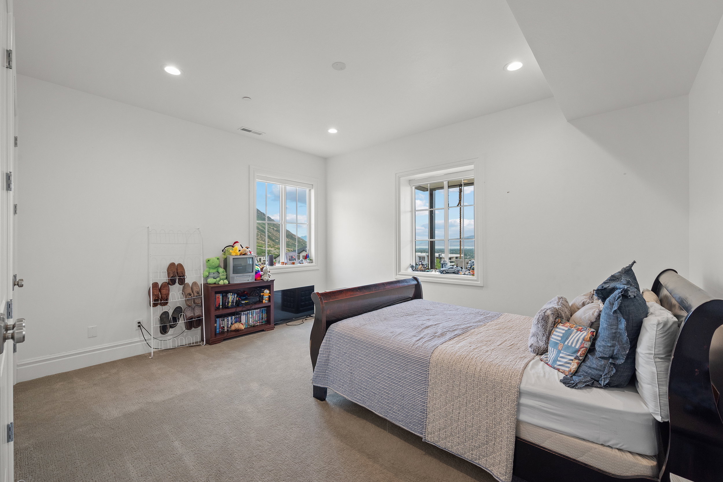 Carpeted room featuring white walls, recessed lighting, and two windows showcasing mountain scenery