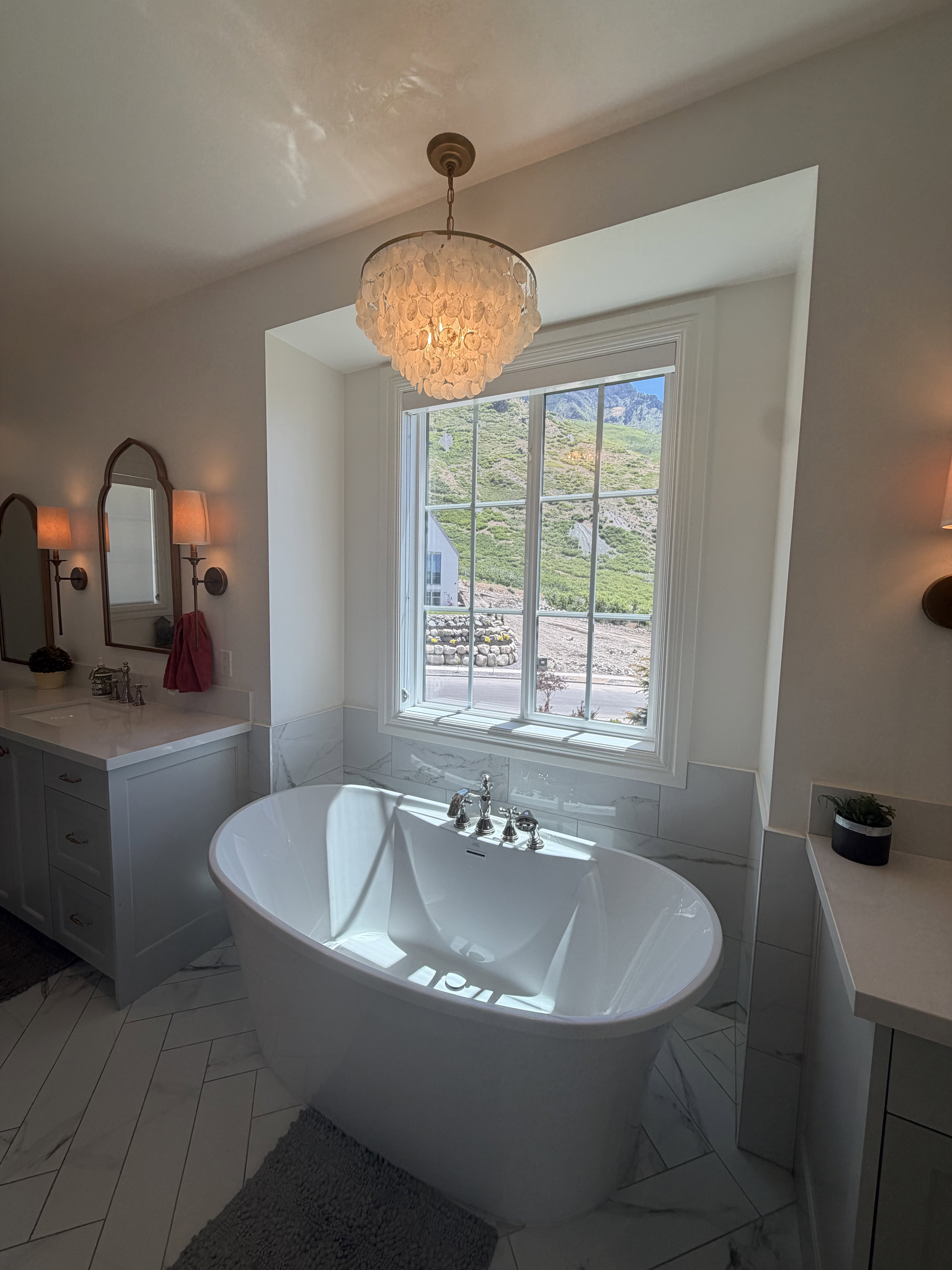 Freestanding soaking tub with polished chrome fixtures, set against a window with mountain scenery