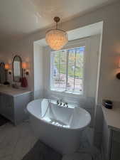 Freestanding soaking tub with polished chrome fixtures, set against a window with mountain scenery
