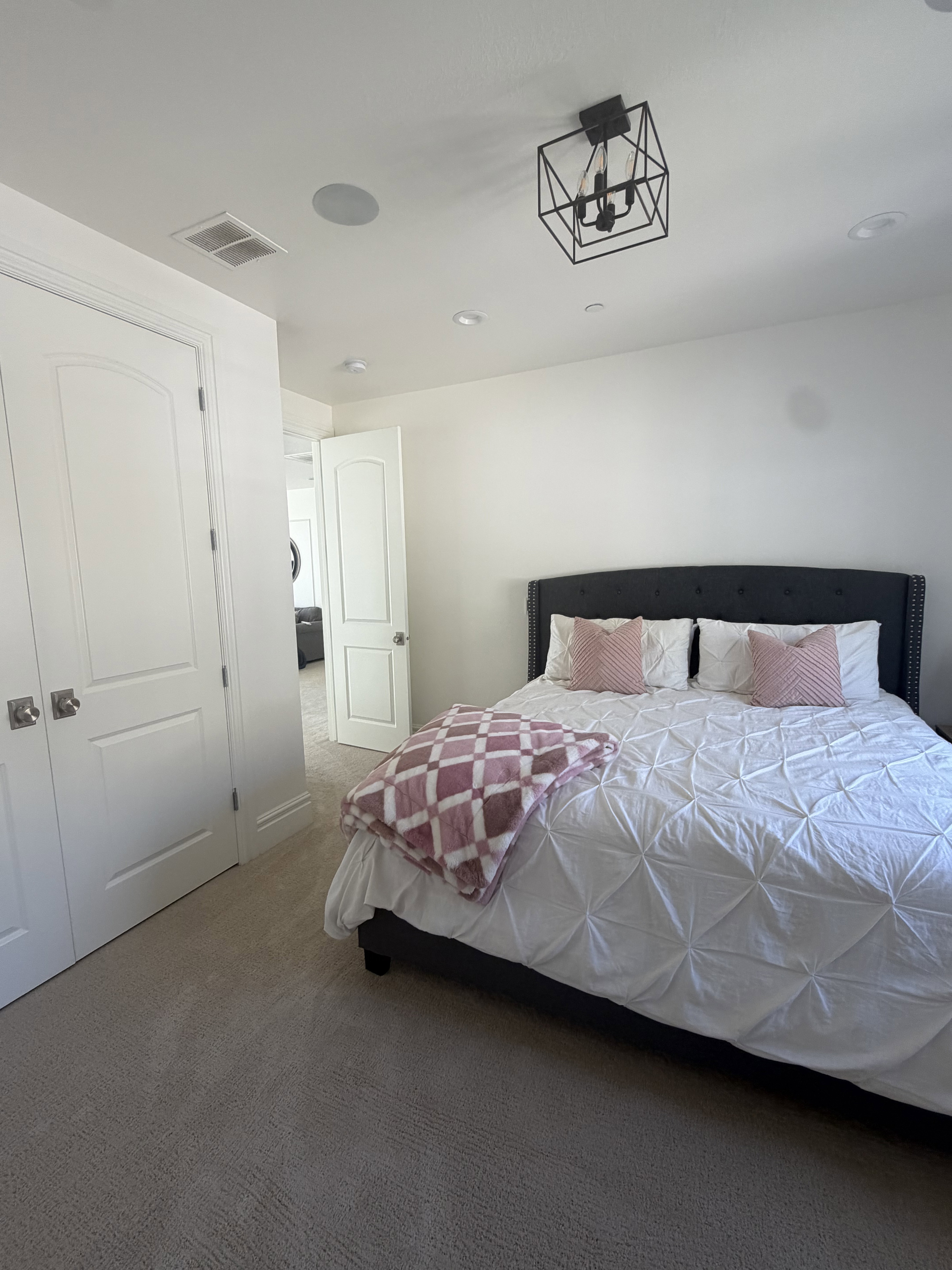 Carpeted room featuring white walls, a black geometric chandelier, recessed lighting, and a built-in ceiling speaker