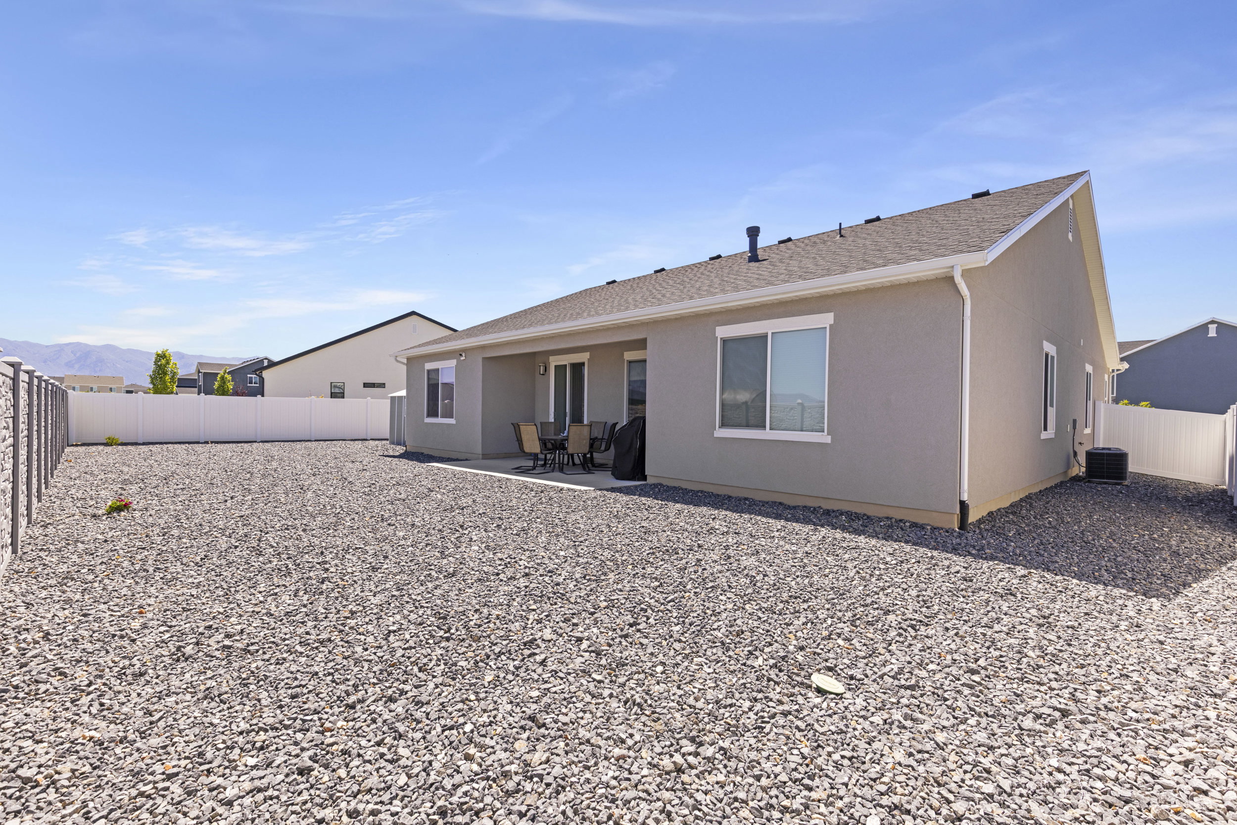 Rear exterior featuring a covered patio, stucco siding, and a gravel landscape