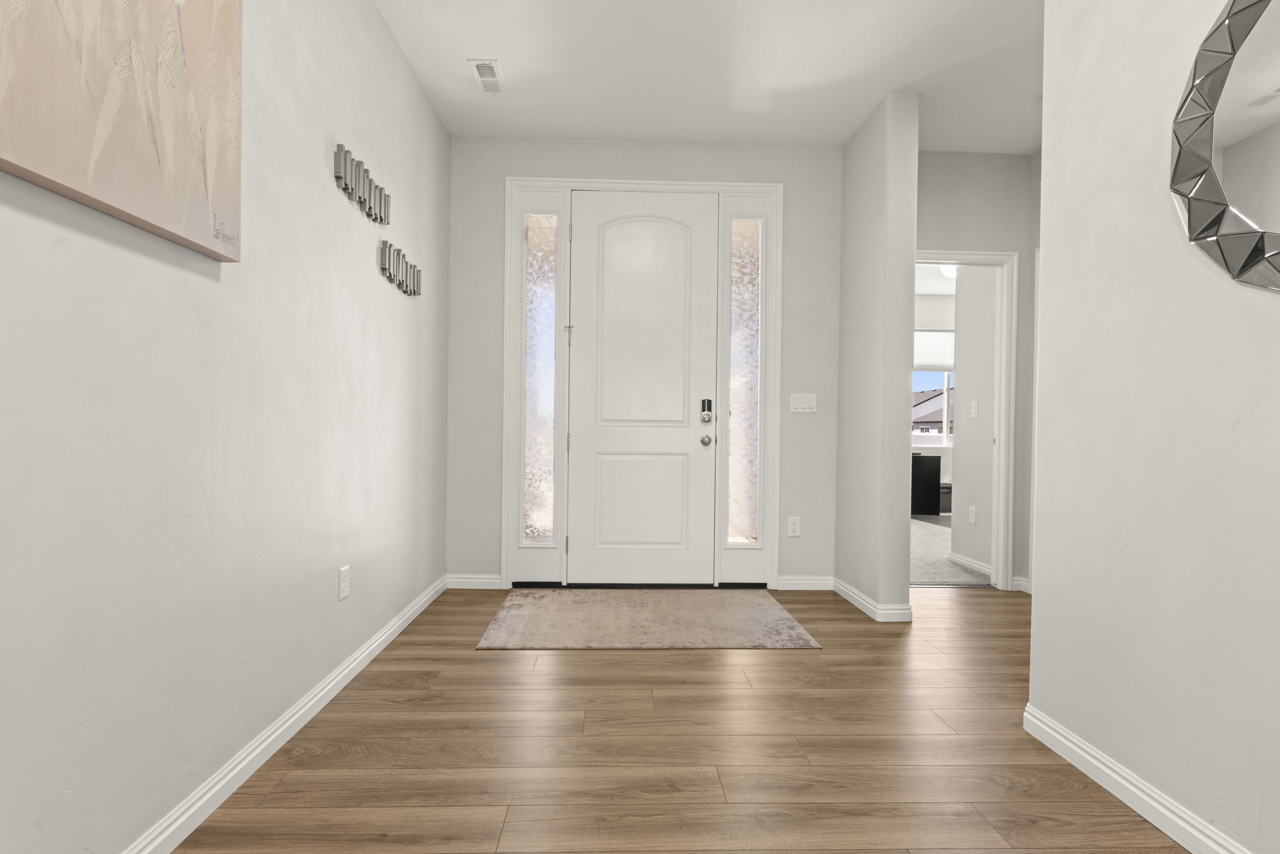 Foyer entrance with a paneled door, decorative glass sidelights, and wood-finish flooring