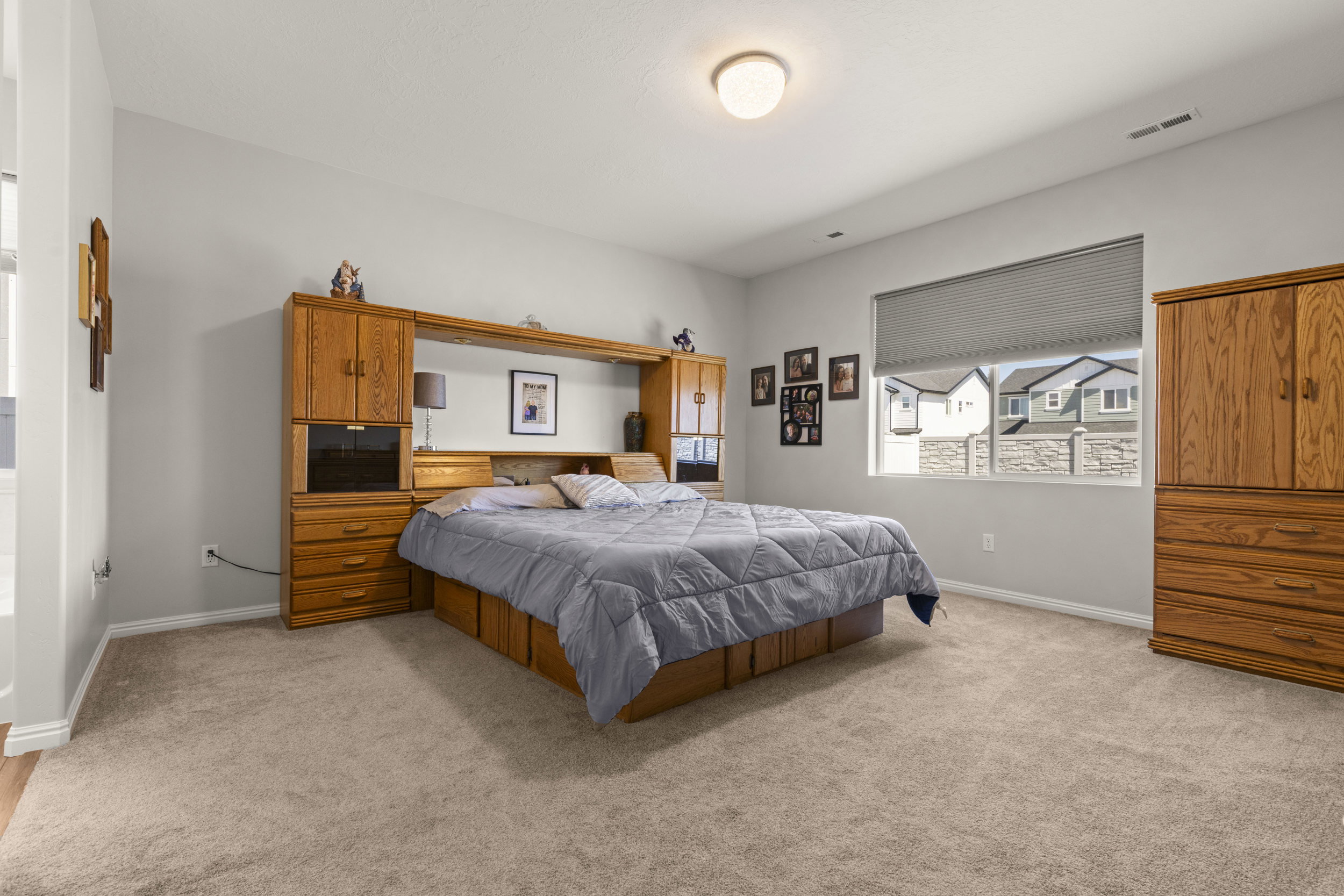 Carpeted bedroom with a single window featuring window treatments and a built-in light fixture