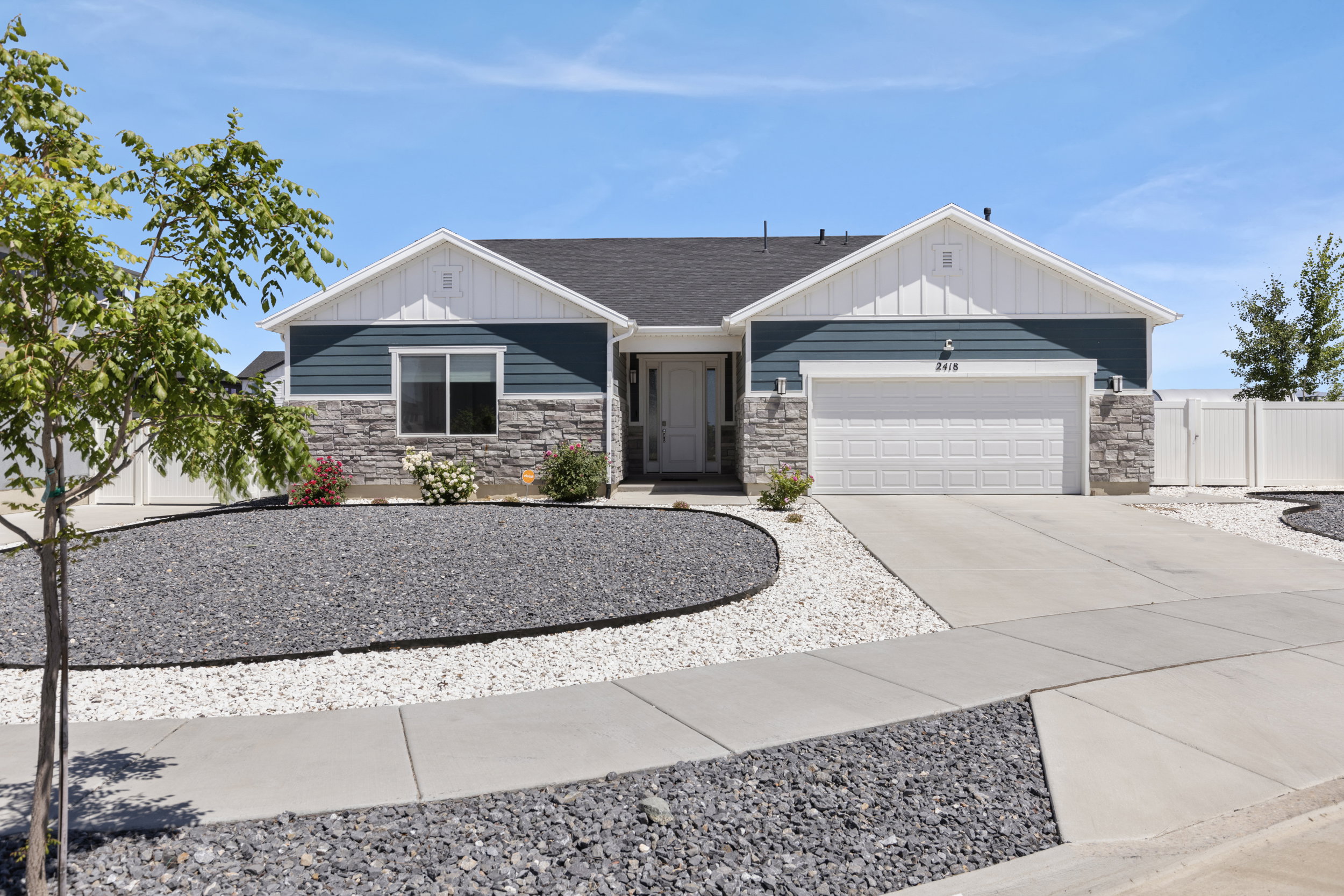 Single-story residence featuring a two-car garage, stone and siding exterior, and a concrete driveway