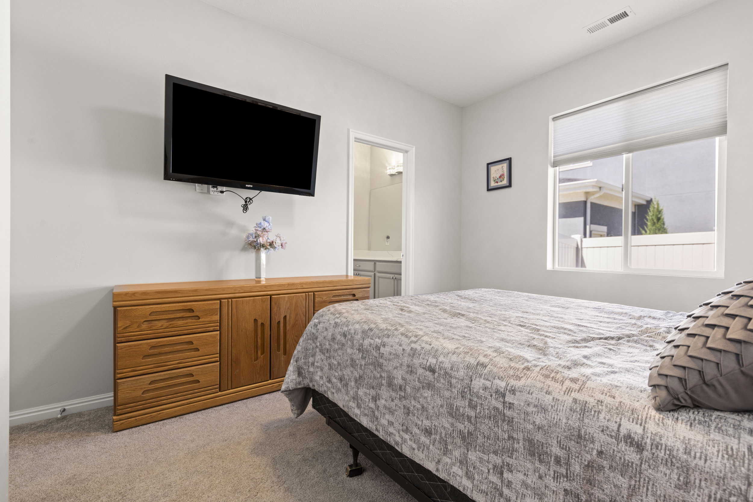 Carpeted room with light grey walls, featuring a window with privacy blinds and an overhead vent