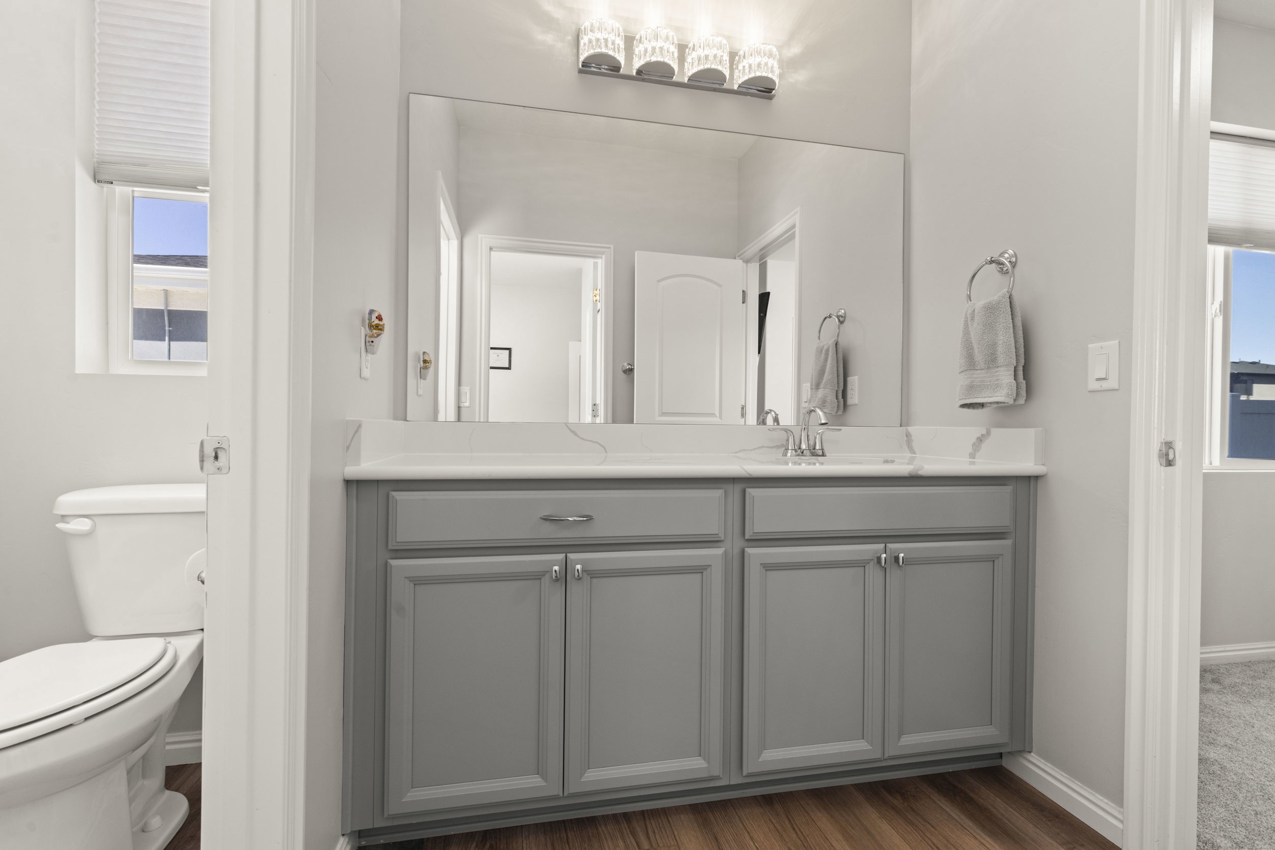 Vanity with a light gray cabinet base, dual undermount sinks, and a white countertop