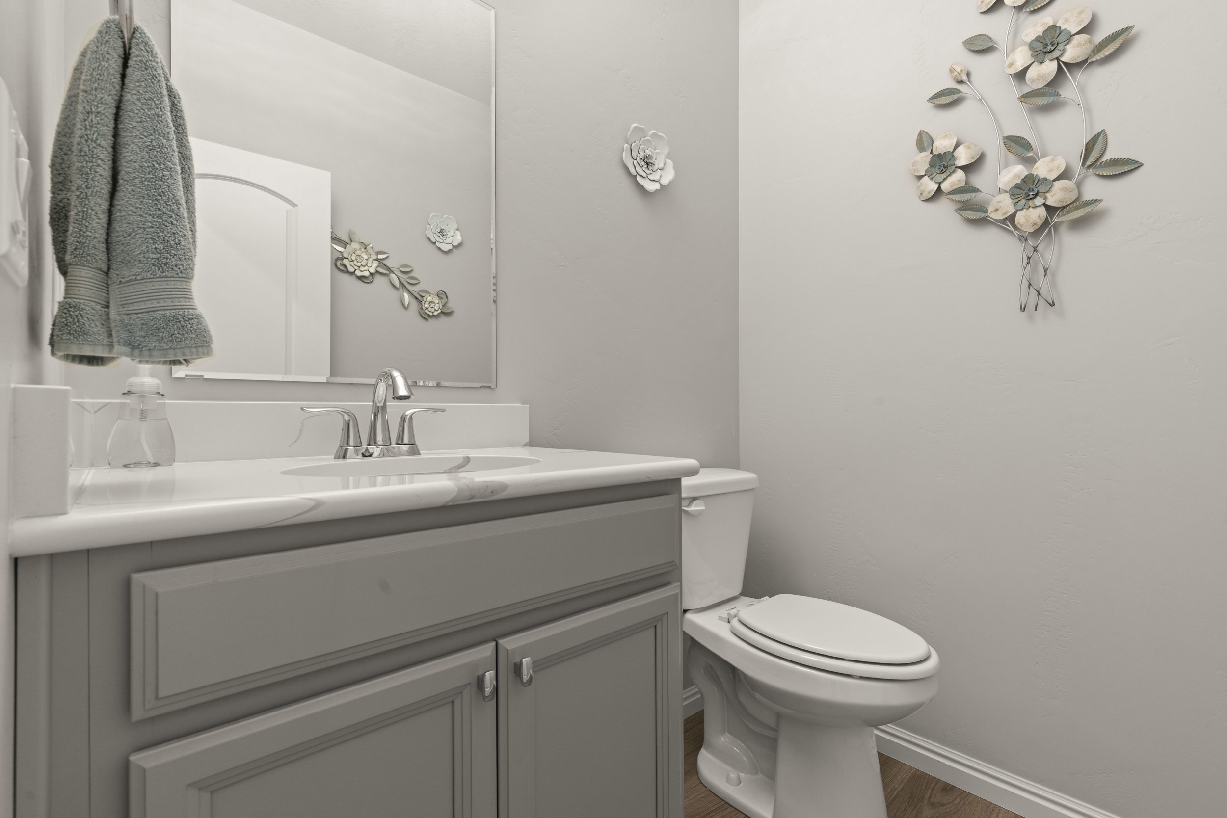 Bathroom featuring a gray vanity with an integrated sink, polished chrome faucet, and a large wall-mounted mirror