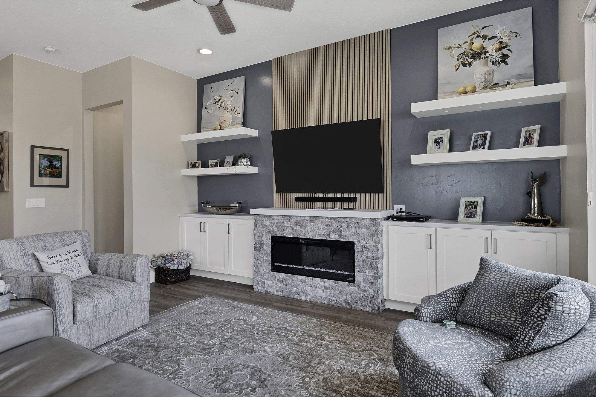 Living area featuring a modern electric fireplace with a stacked stone surround, flanked by white built-in cabinetry with counter space
