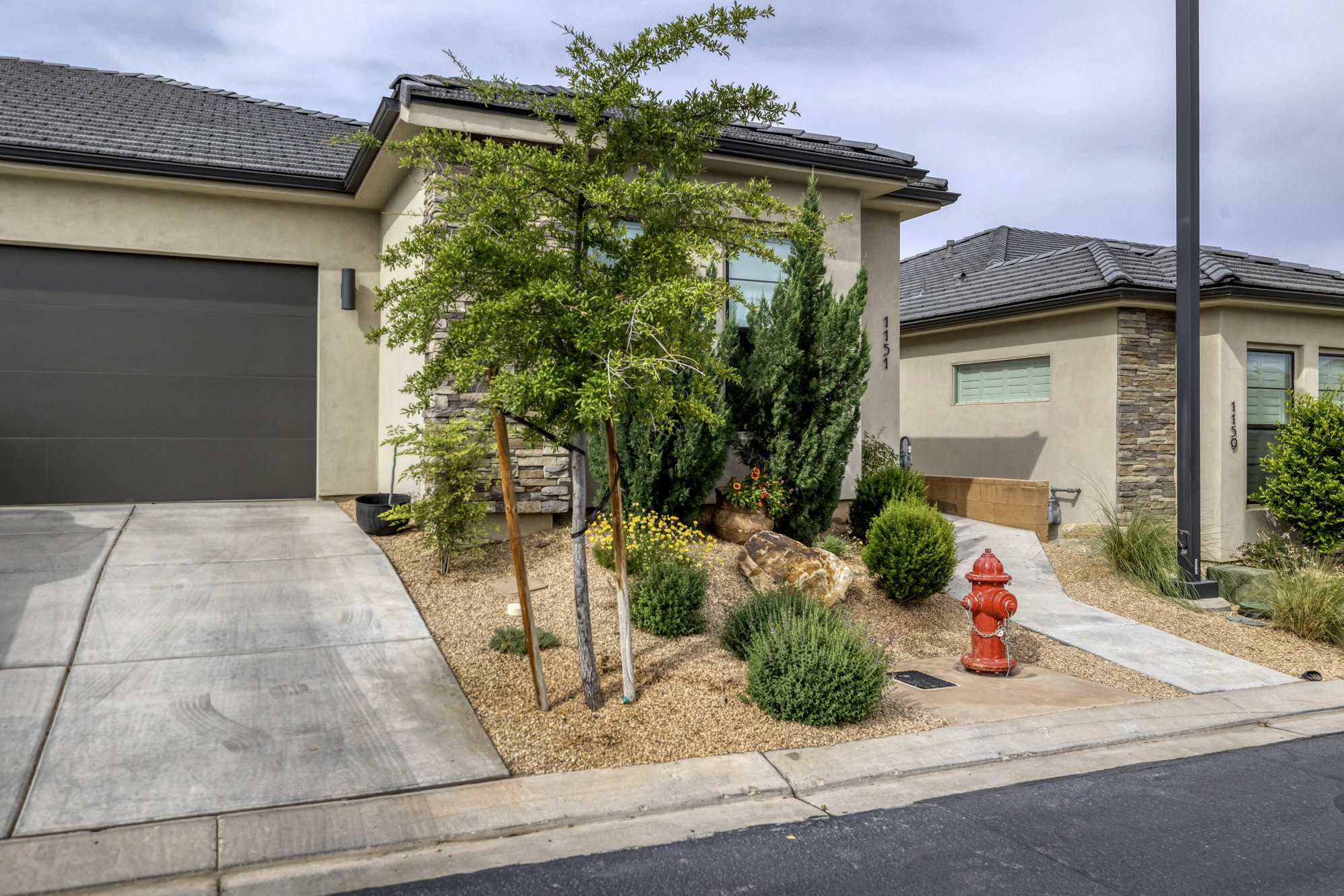 Contemporary stucco exterior featuring a stone accent wall, an attached garage, and a concrete driveway