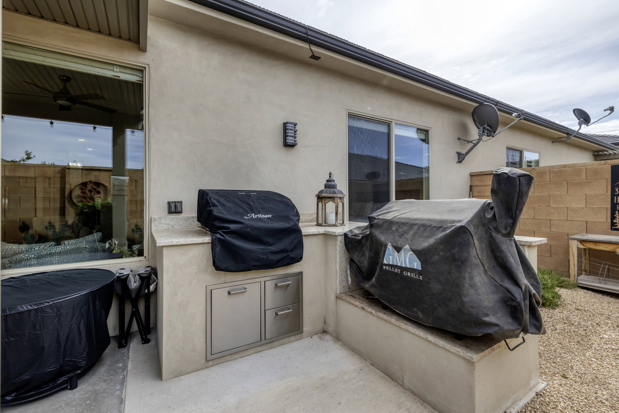 Outdoor kitchen featuring built-in stainless steel cabinetry, a light-colored countertop, and a stucco finish