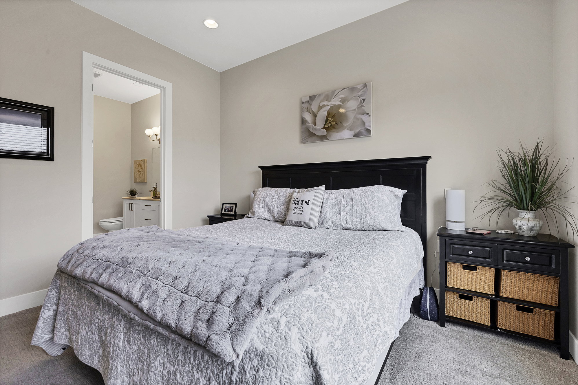 Recessed ceiling lighting illuminates a bedroom with neutral wall tones and plush carpeting