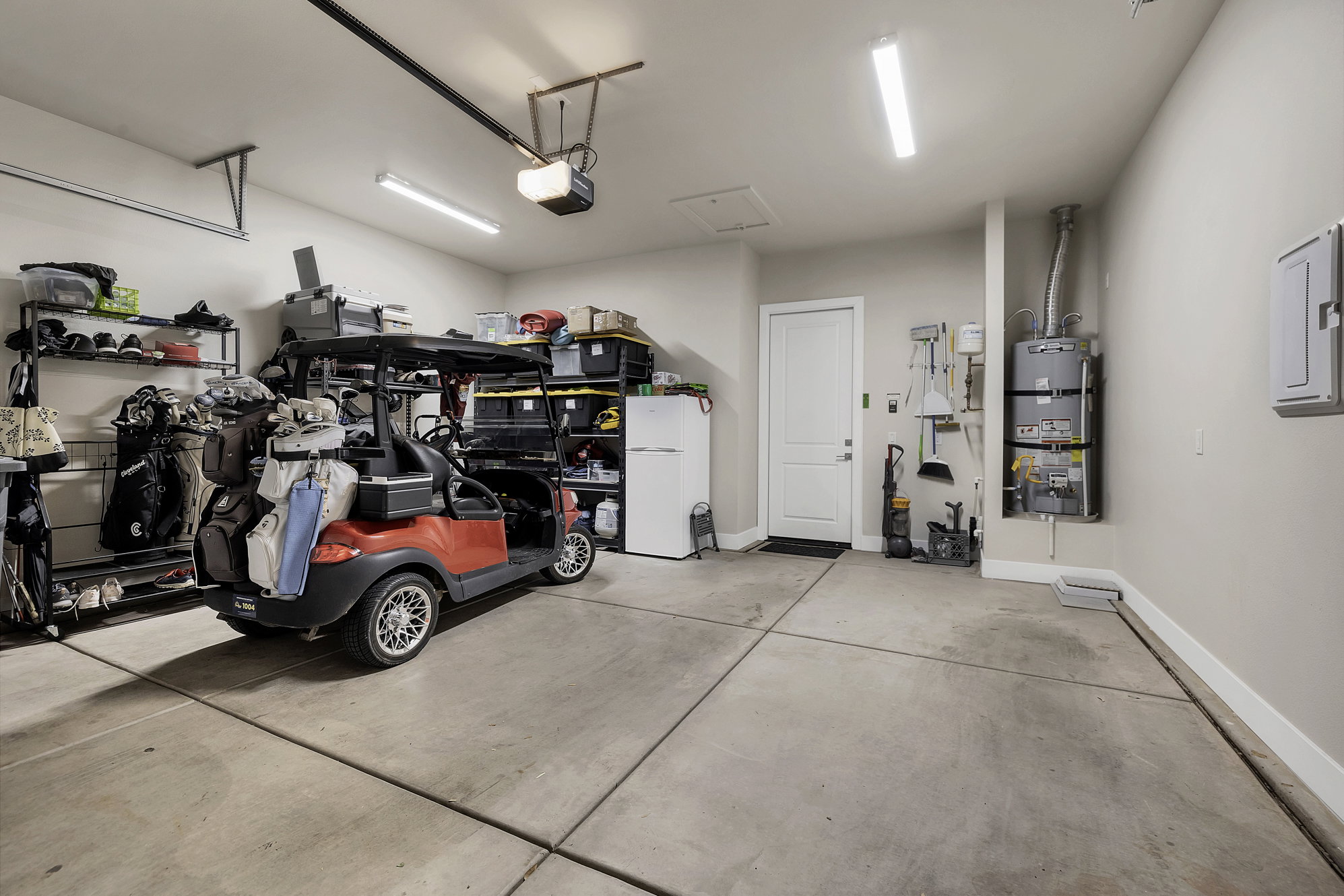 Spacious garage featuring a concrete floor, overhead lighting, and an internal access door