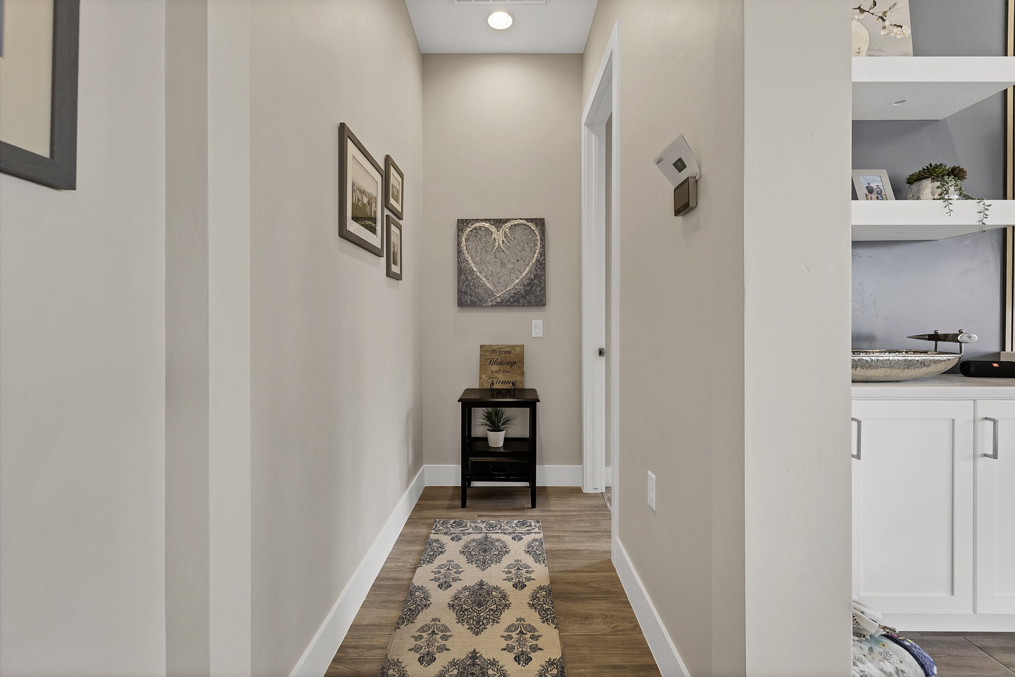 Hallway featuring light neutral wall paint, wood-finish flooring, and white baseboards