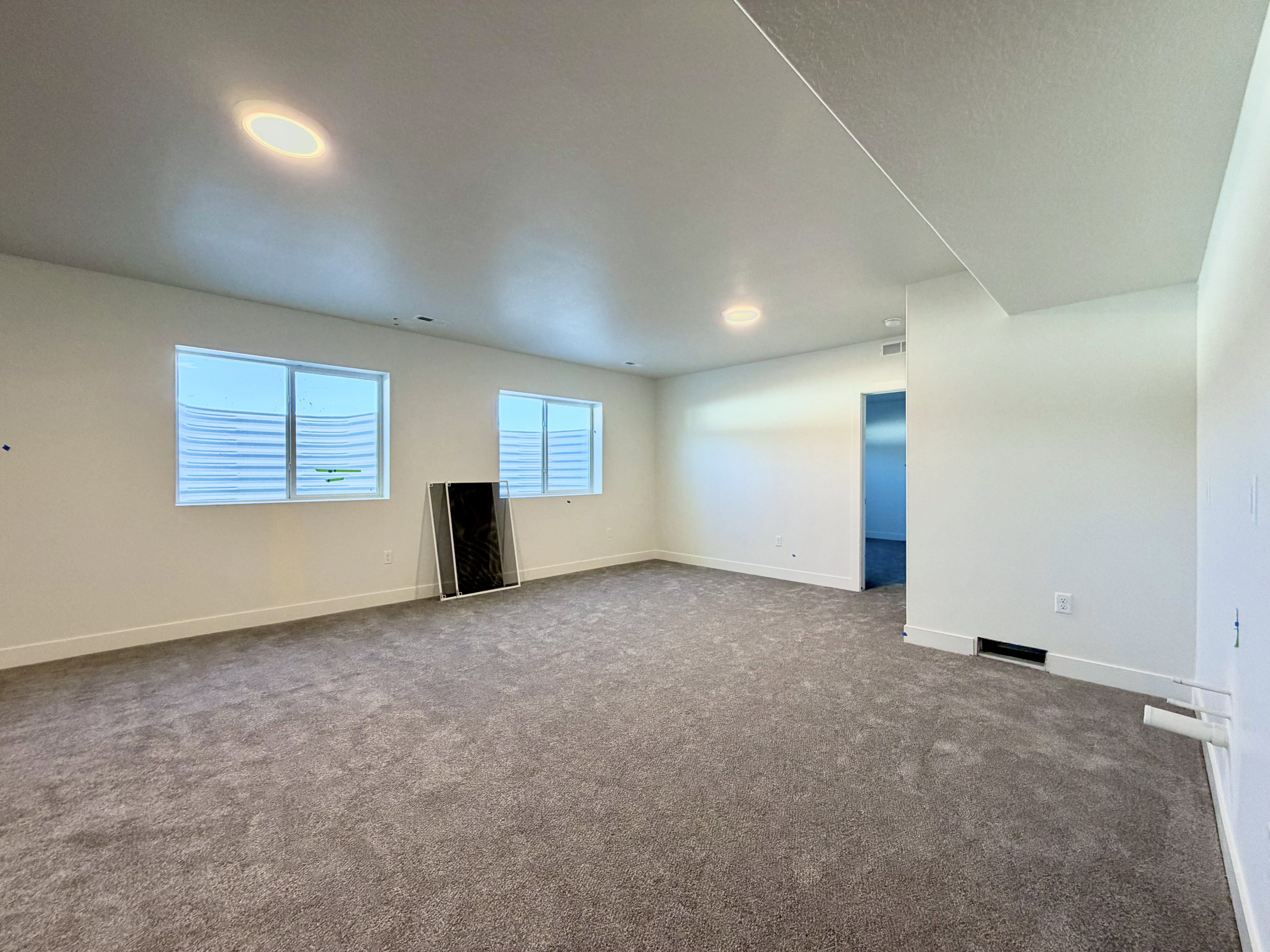 Spacious carpeted room featuring two egress windows, recessed ceiling lighting, and neutral wall finishes