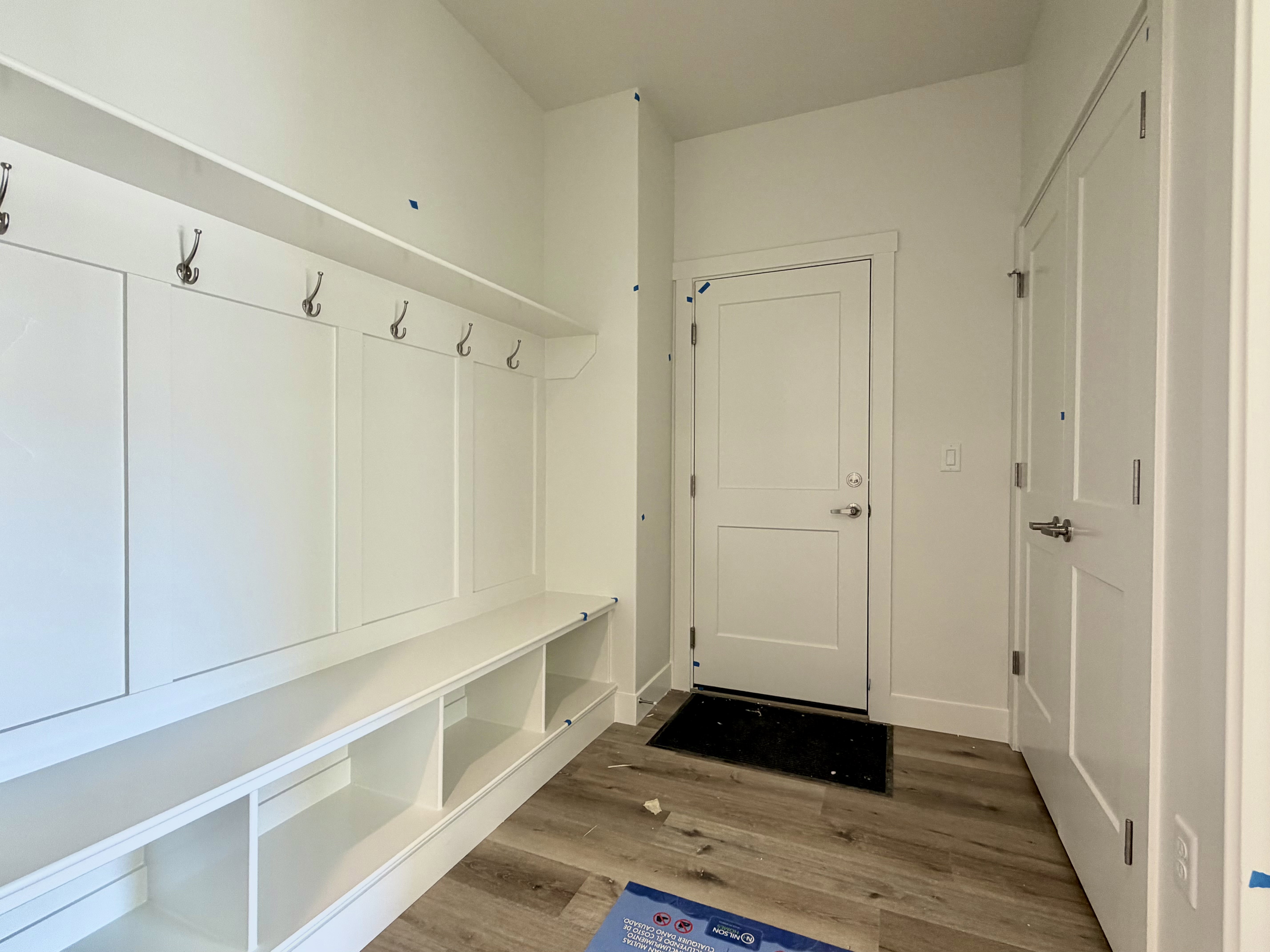 Built-in mudroom features paneling, coat hooks, and integrated storage cubbies