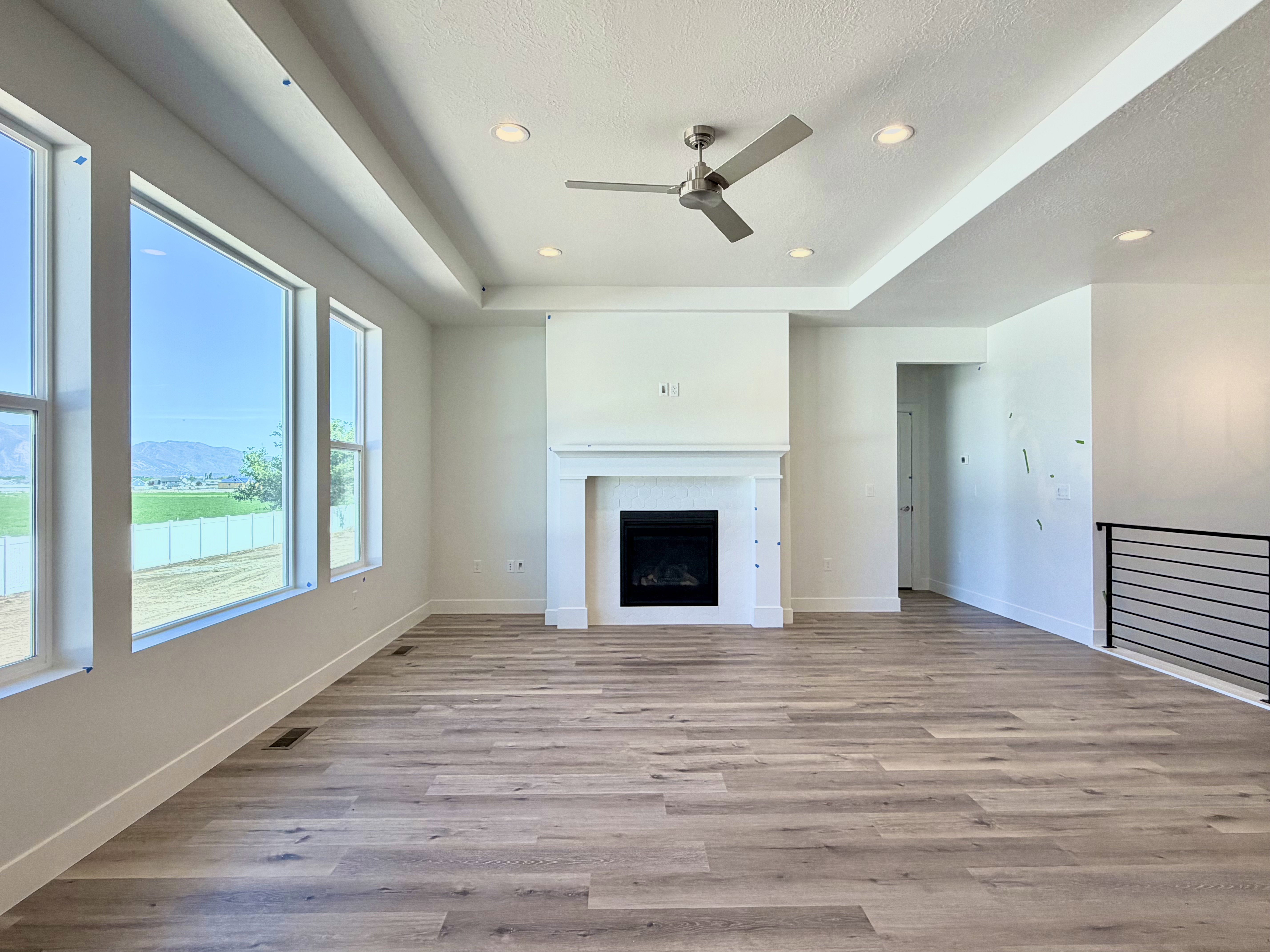 Open concept living space featuring wood-finish flooring, a tray ceiling, and a contemporary ceiling fan