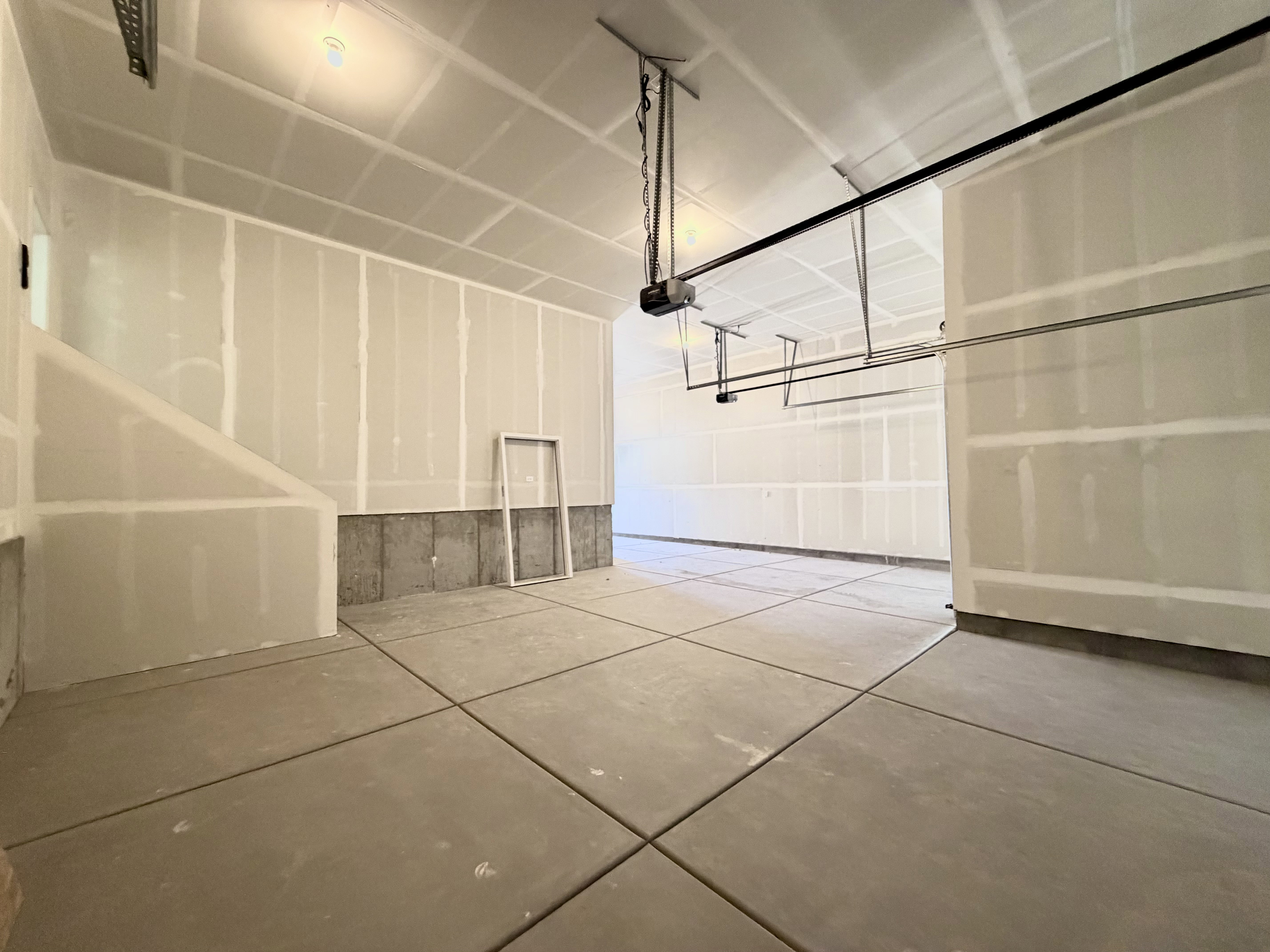 Spacious garage with concrete flooring, exposed ceiling joists, and a partial concrete foundation wall