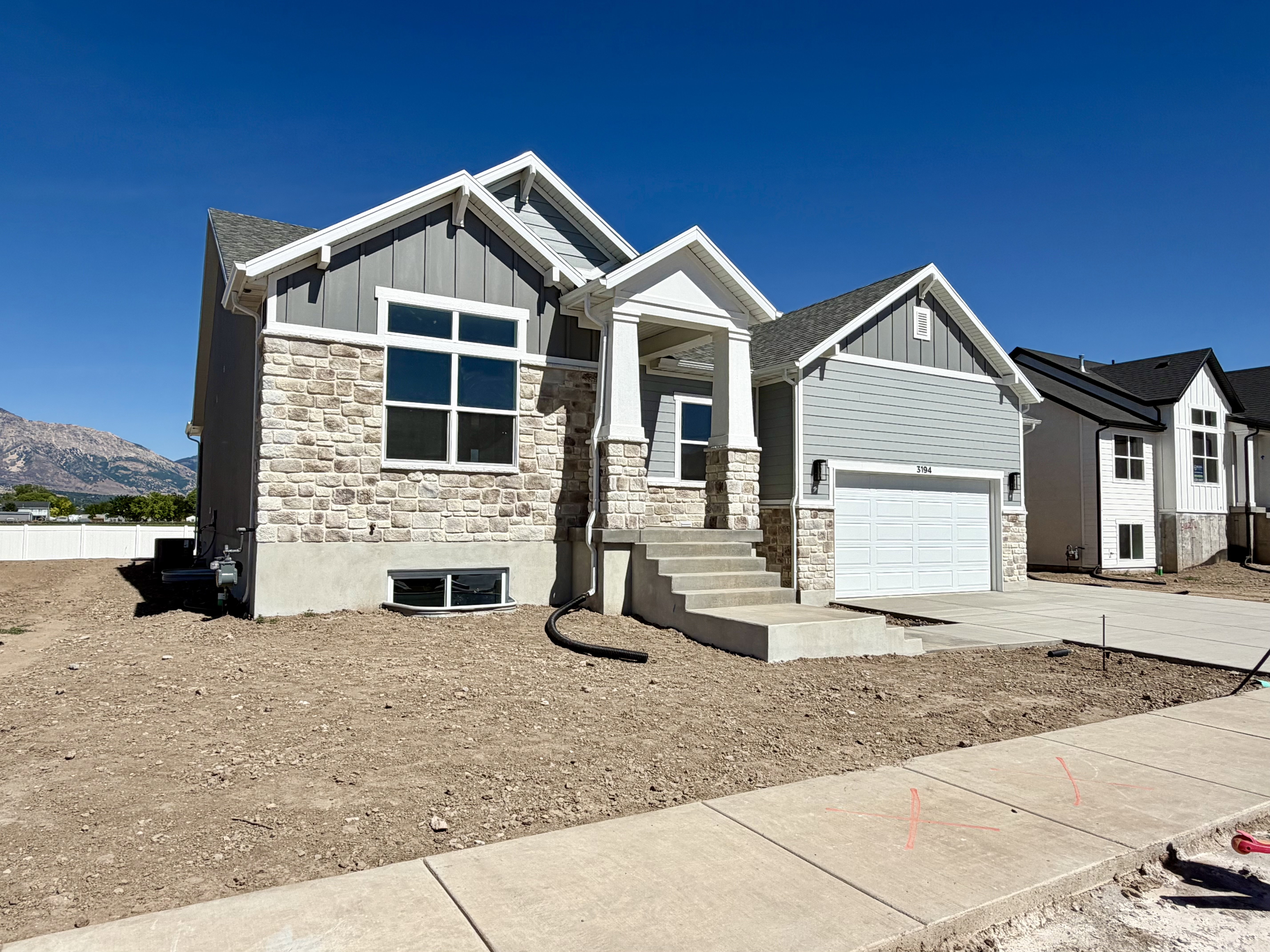 Contemporary exterior featuring light grey siding and stone veneer accents