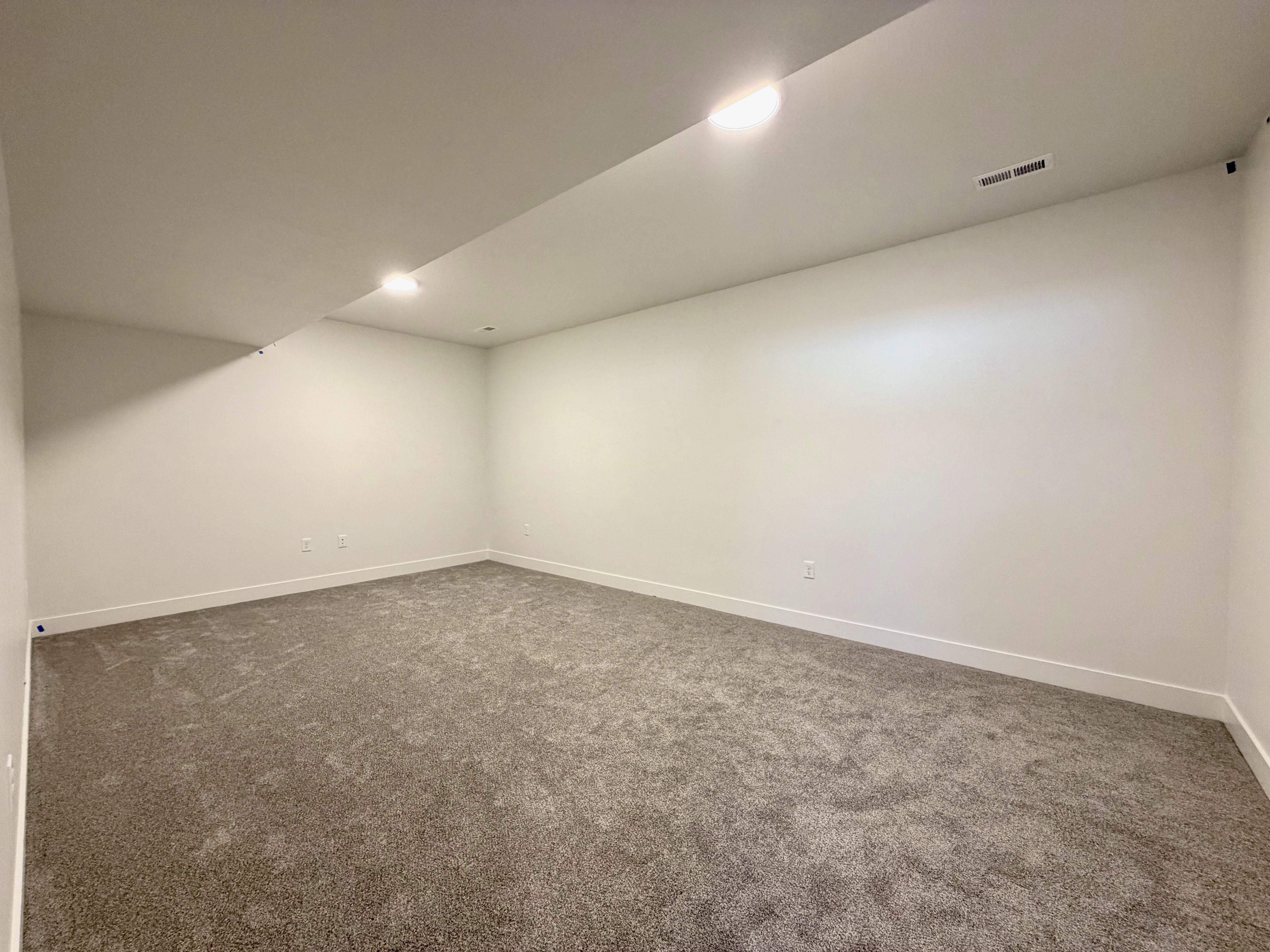 Spacious room with new carpet flooring, crisp white walls, recessed lighting, and white baseboards
