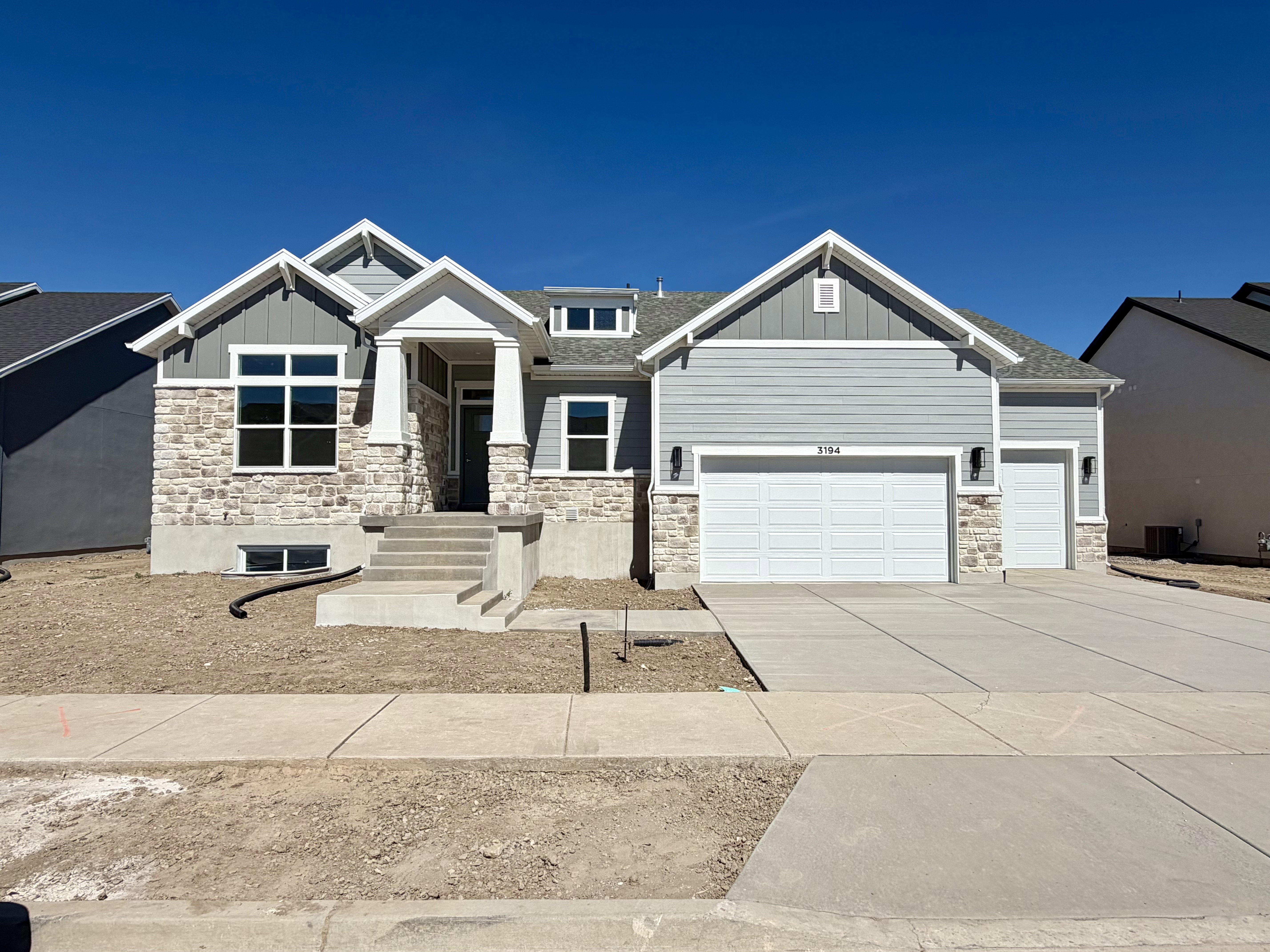 Contemporary home featuring a light gray siding facade and stone accents