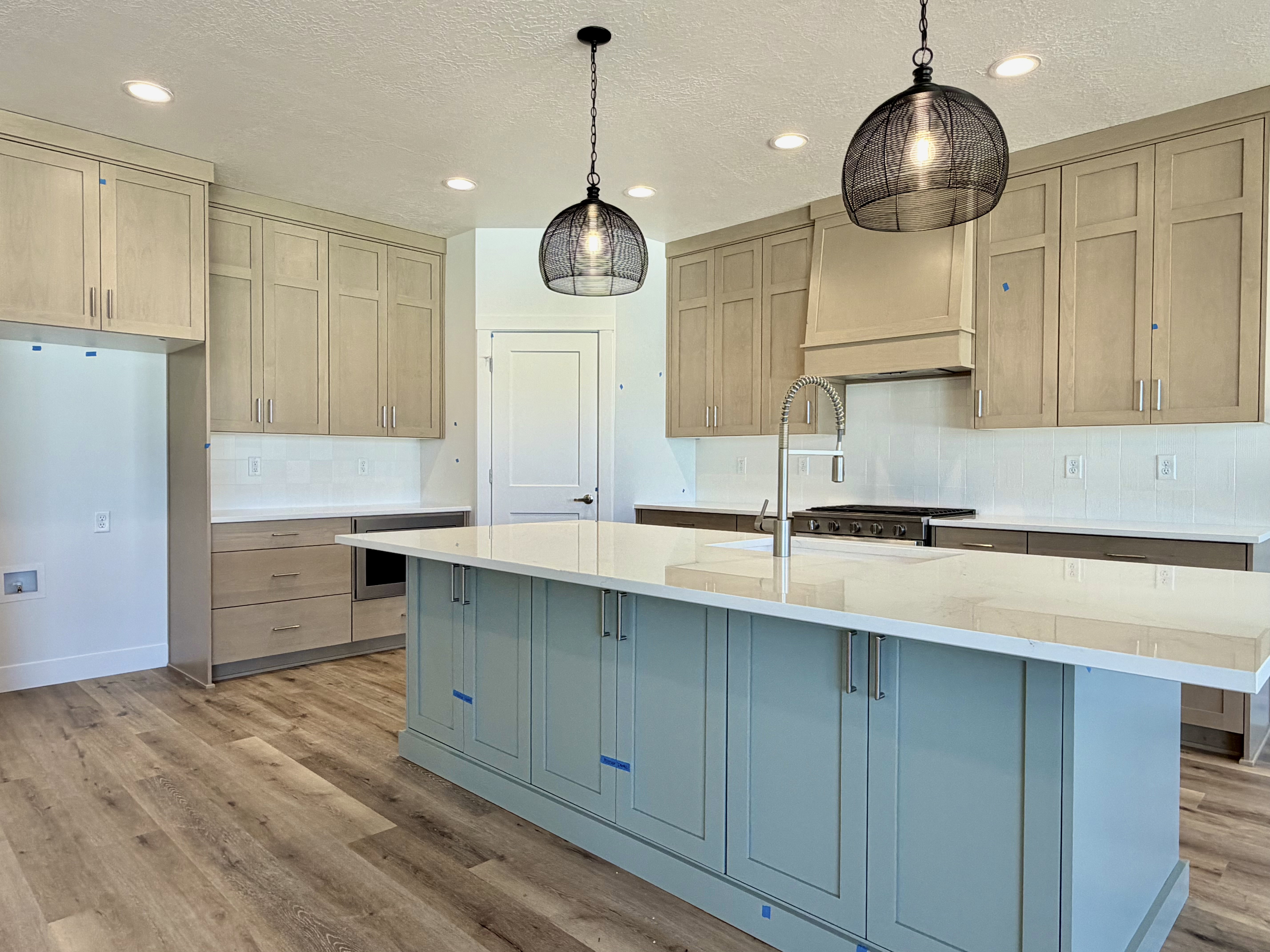 Kitchen island with a light-colored countertop, complemented by two distinctive wire-cage pendant lights and recessed ceiling lighting