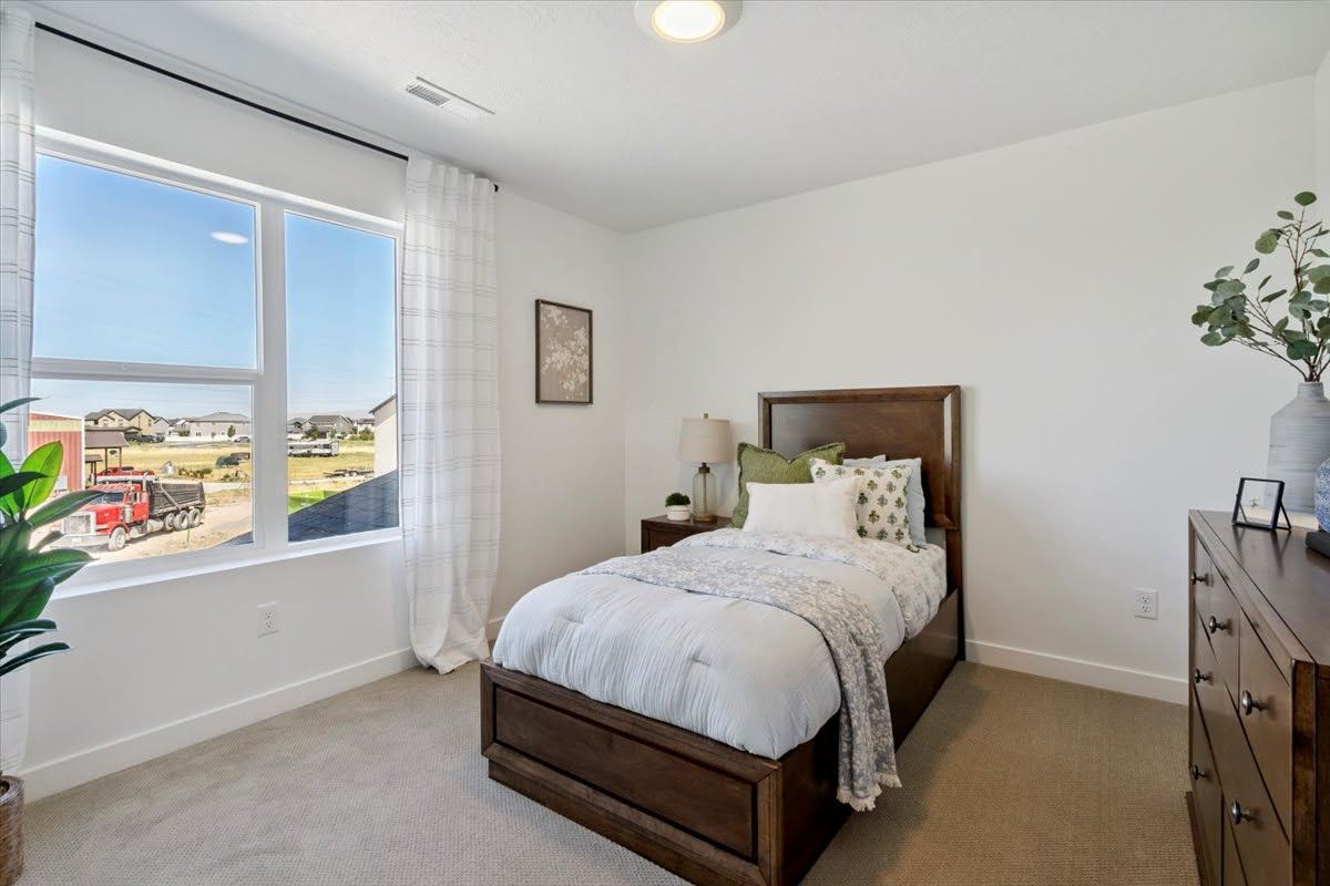 Bedroom featuring a large window, neutral carpet flooring, white walls, a single ceiling light fixture, and white baseboards