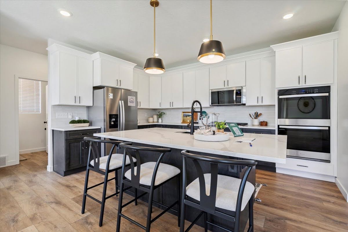 Modern kitchen featuring an expansive center island with seating, stainless steel appliances, and a built-in double oven