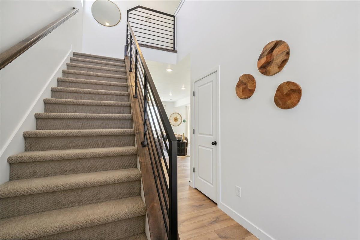 Carpeted staircase with dark wood handrail and black metal balusters