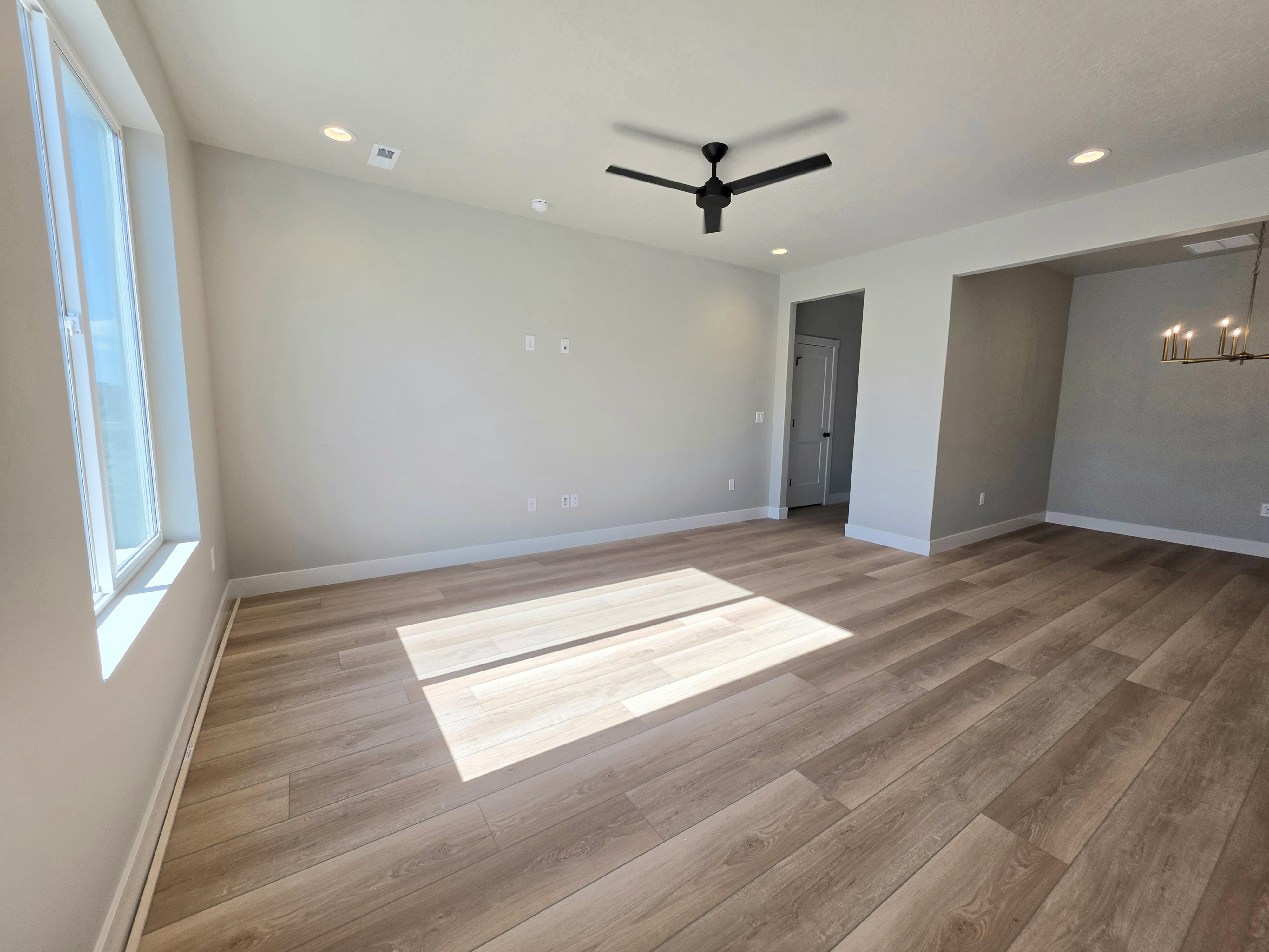 Spacious room featuring wood-finish flooring and a contemporary black ceiling fan