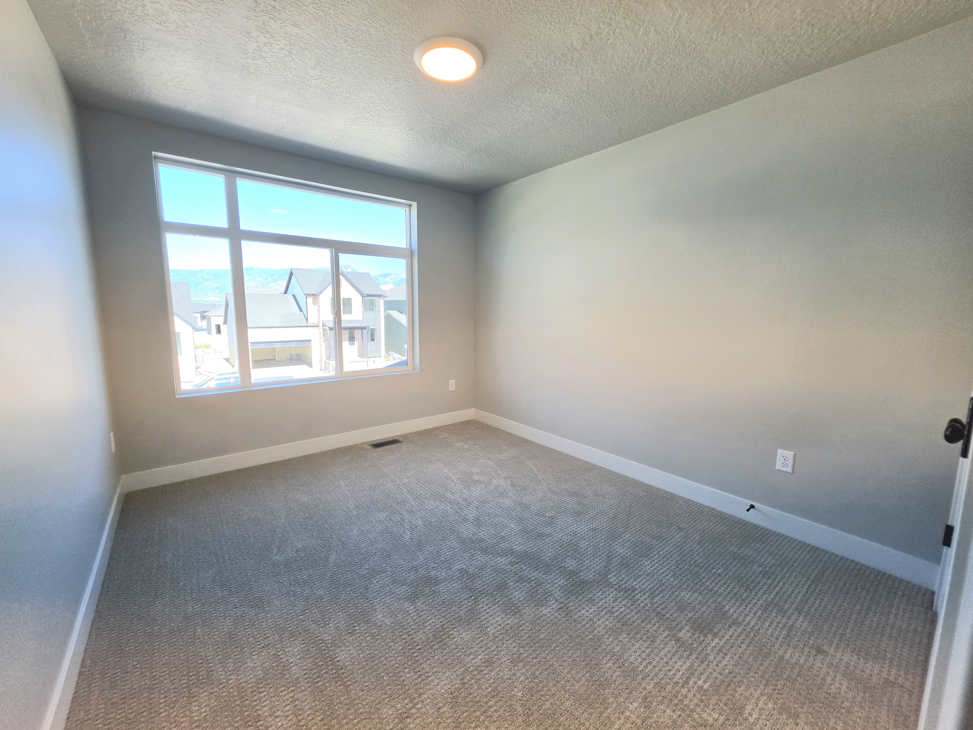 Room with light gray walls, white baseboards, and neutral patterned carpeting