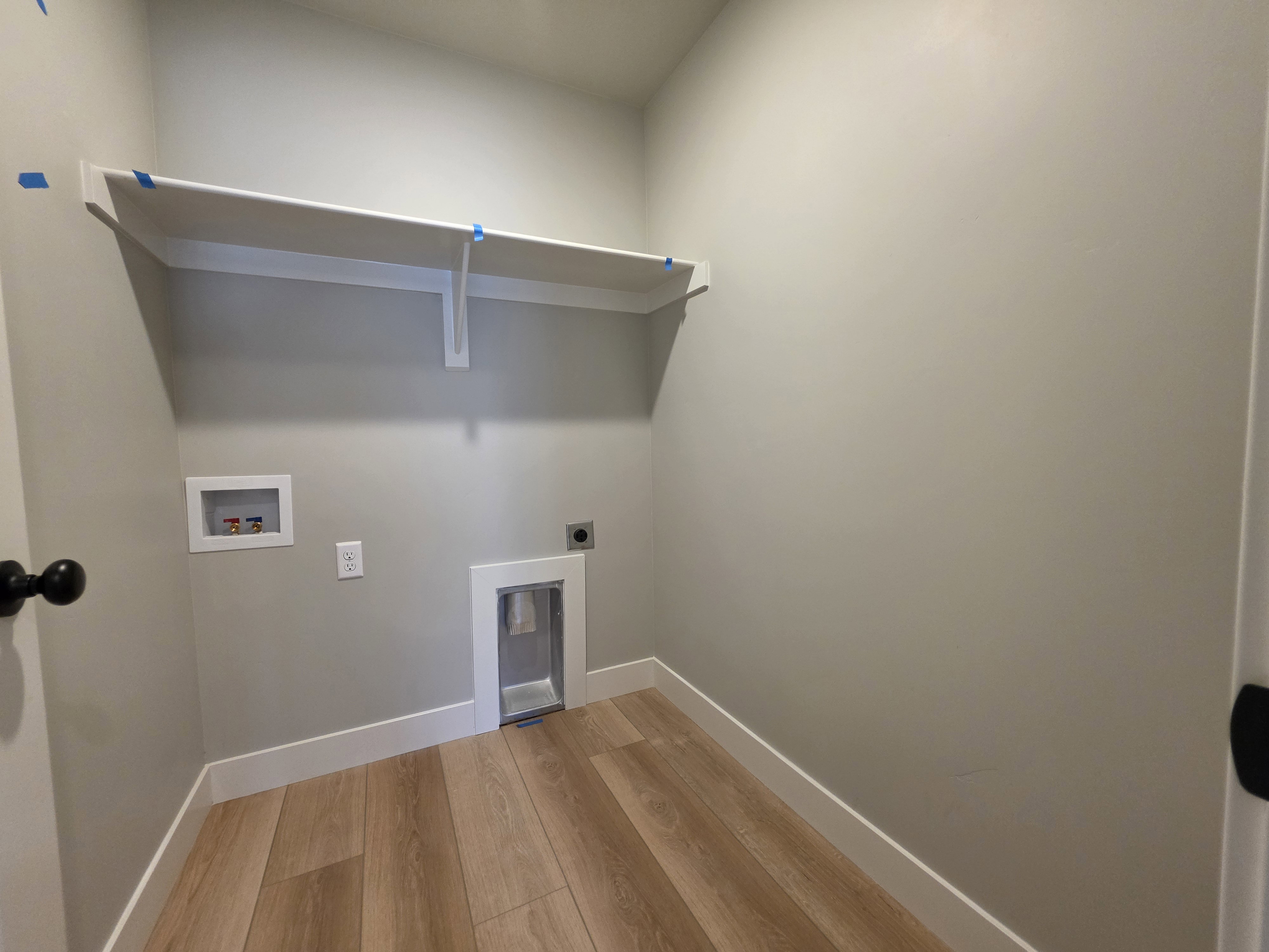 Dedicated utility space featuring wood-finish flooring and light gray walls