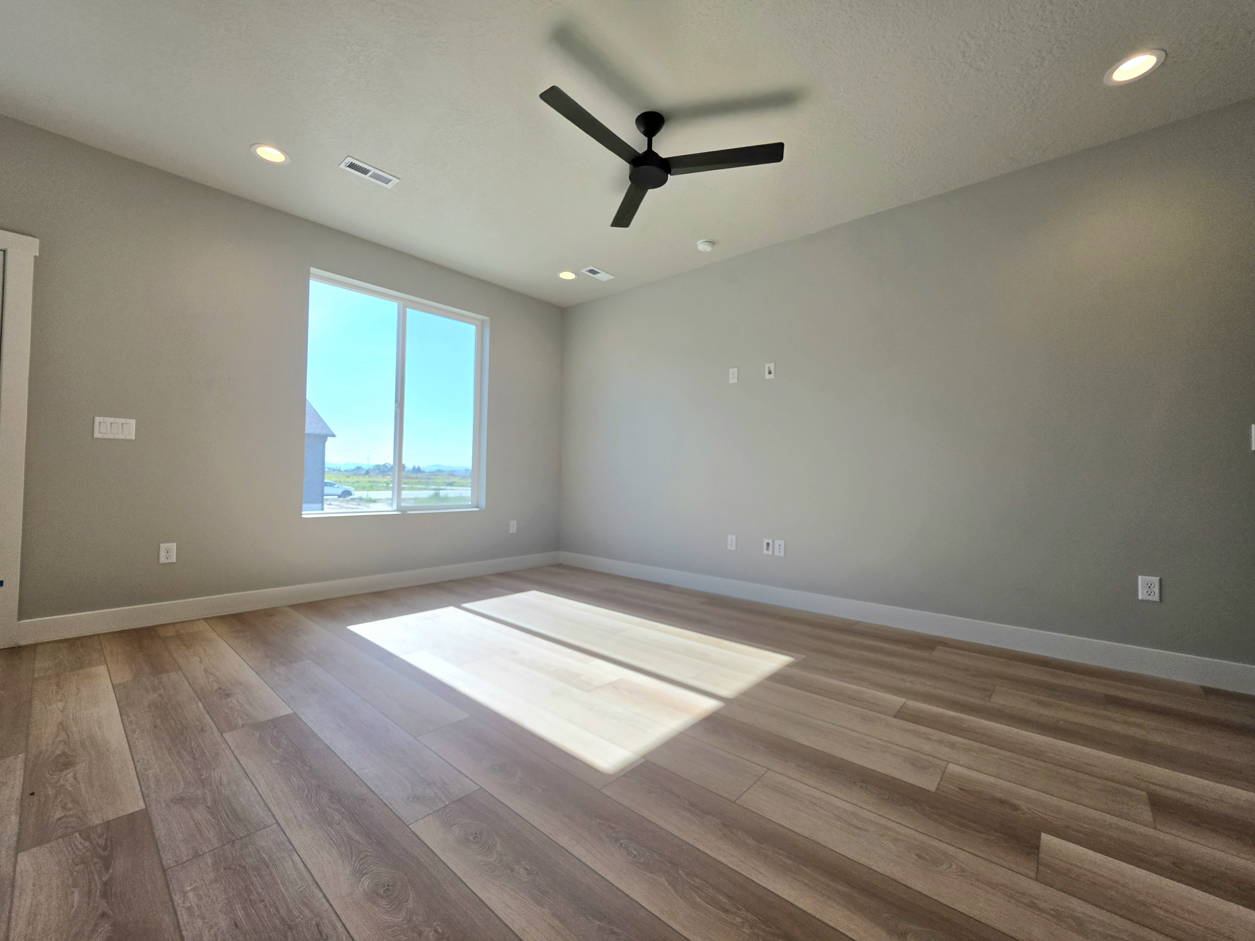 Spacious room featuring wood-finish flooring, a large window, recessed lighting, and a ceiling fan