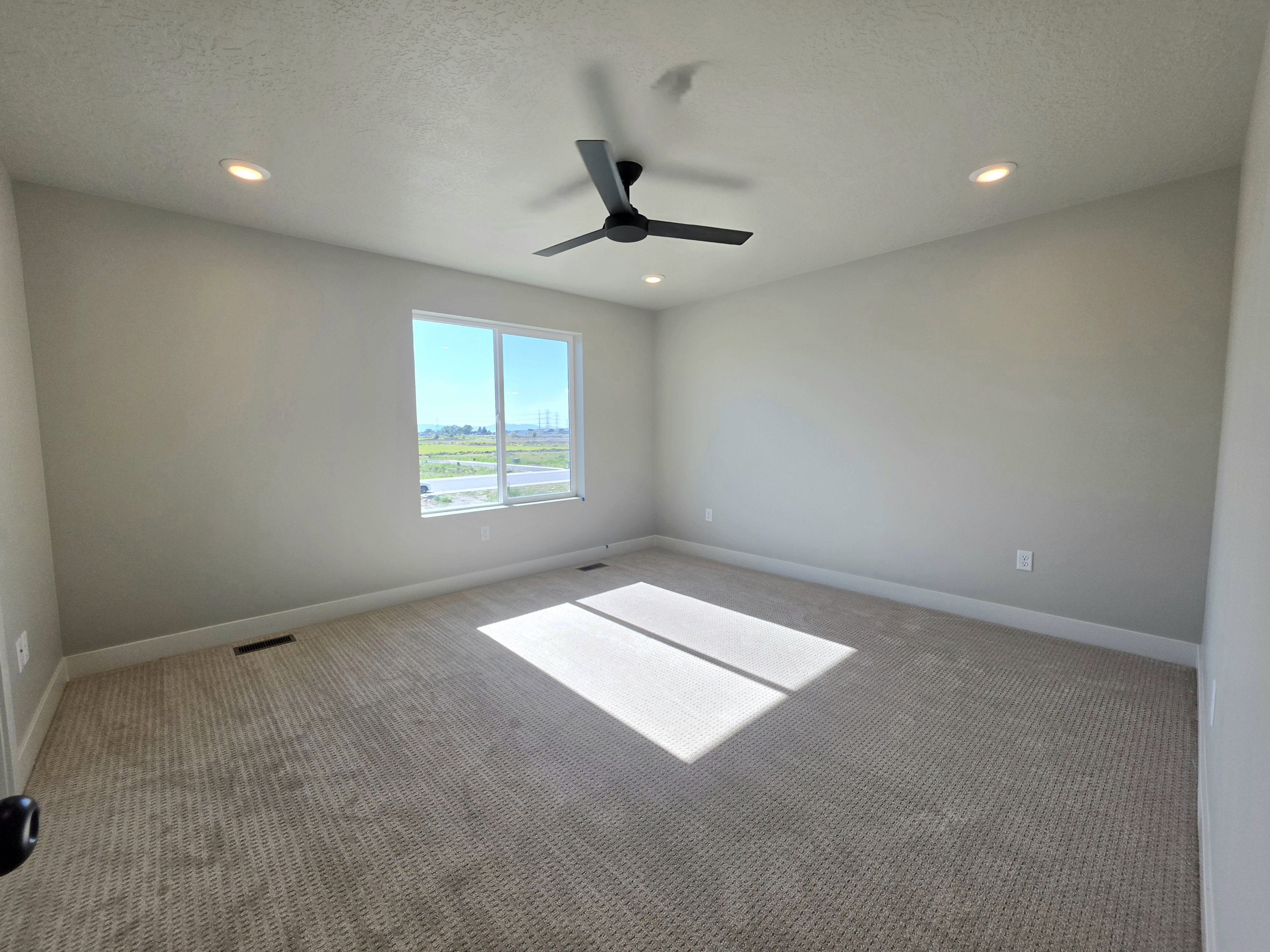 Spacious room featuring neutral carpeting, recessed lighting, and a modern ceiling fan