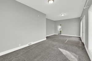 Spacious room featuring gray carpet flooring, light gray wall paint, and white trim