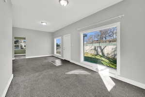 Spacious room featuring neutral grey walls and dark grey carpeting
