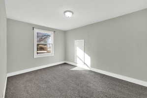 Bedroom featuring light grey walls, white trim, and grey carpet flooring