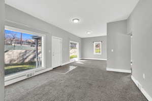 Spacious living area featuring neutral gray wall paint, dark gray carpeting, and white trim