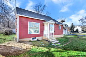 Red siding exterior with a dark shingle roof, featuring a covered entry porch with white railings and steps