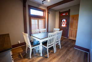 Dining area featuring dark wood-finish flooring, a decorative transom window with wood shutters, and a stained glass entry door