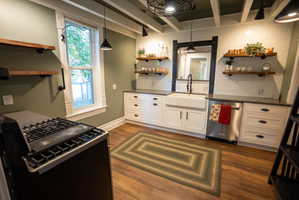 Modern kitchen featuring a farmhouse-style sink, white cabinetry, dark countertops, and stainless steel appliances