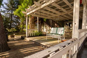 Expansive outdoor decking featuring a covered patio with string lighting, painted wooden railing, and a visible exterior staircase