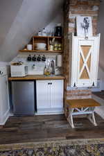 Compact kitchen area featuring wood-finish flooring, white cabinetry, and a stainless steel undercounter refrigerator