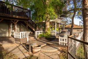 Multi-level outdoor deck featuring a pergola, wood railings, built-in planters, and an exterior staircase