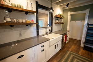 Kitchenette featuring a farmhouse sink, dark stone-finish countertops, subway tile backsplash, and wood-finish flooring