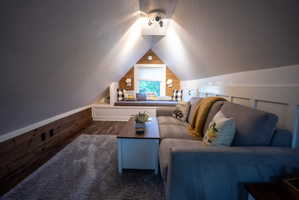 Attic space featuring wood-finish flooring, a built-in window seat, and sloped ceilings
