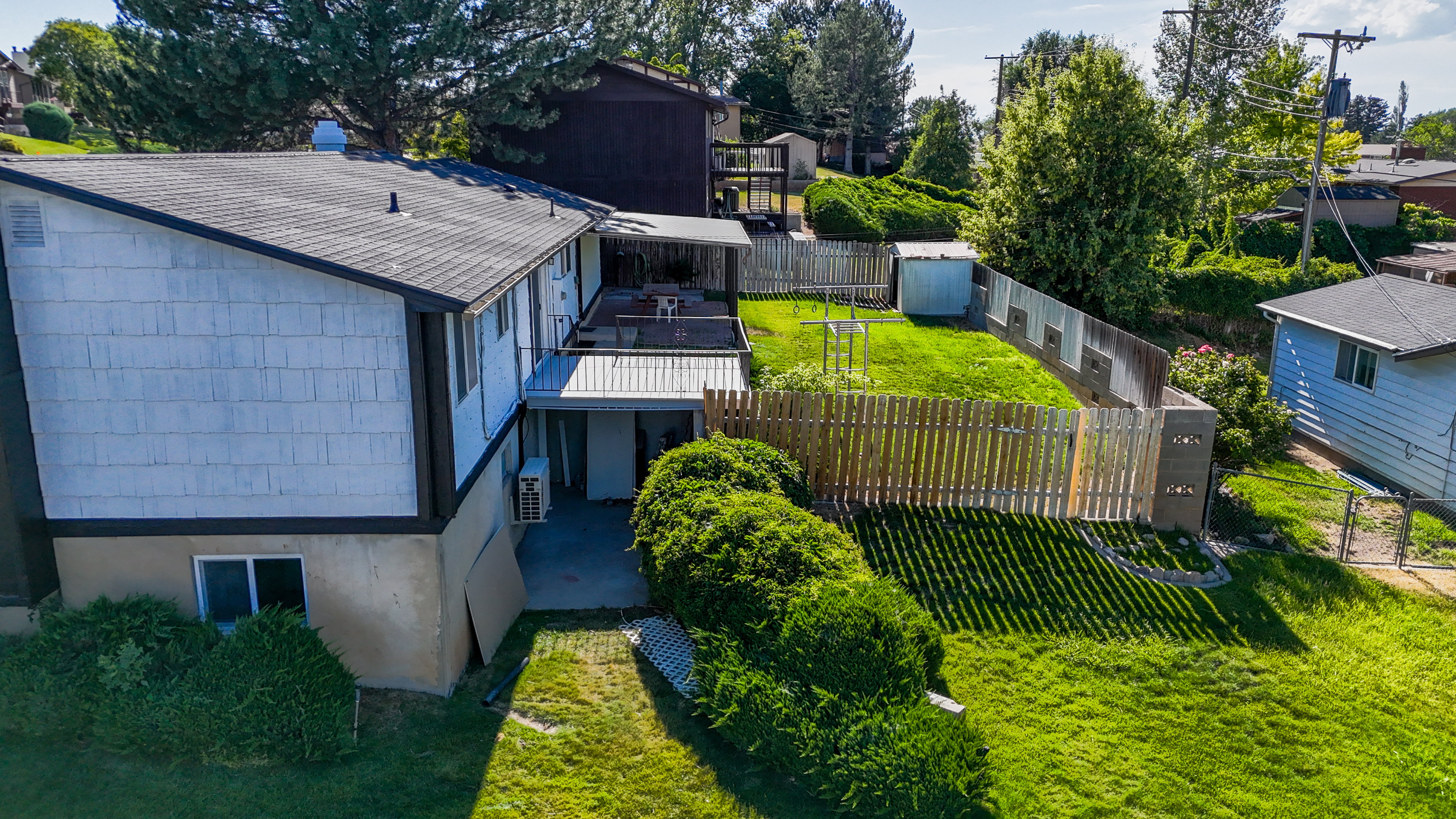 Exterior featuring white shingle siding with dark trim, a dark asphalt shingle roof, and a ground-level patio