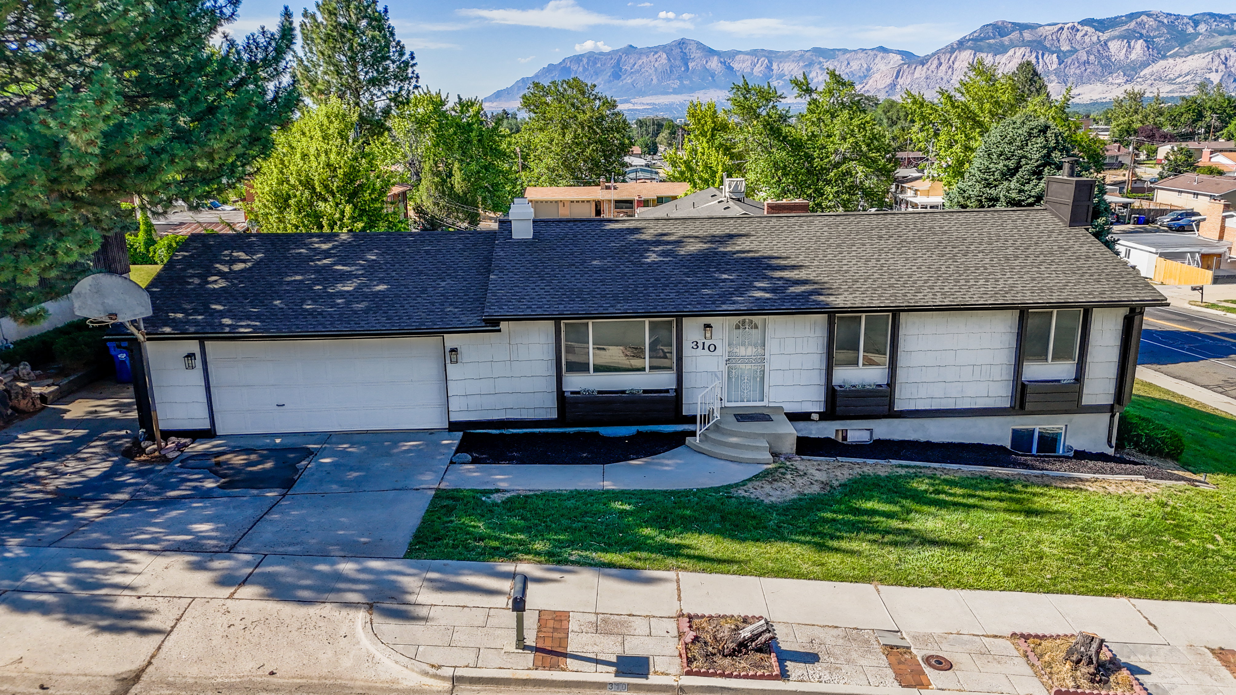 Ranch-style residence featuring a dark shingle roof, white siding, and an attached two-car garage