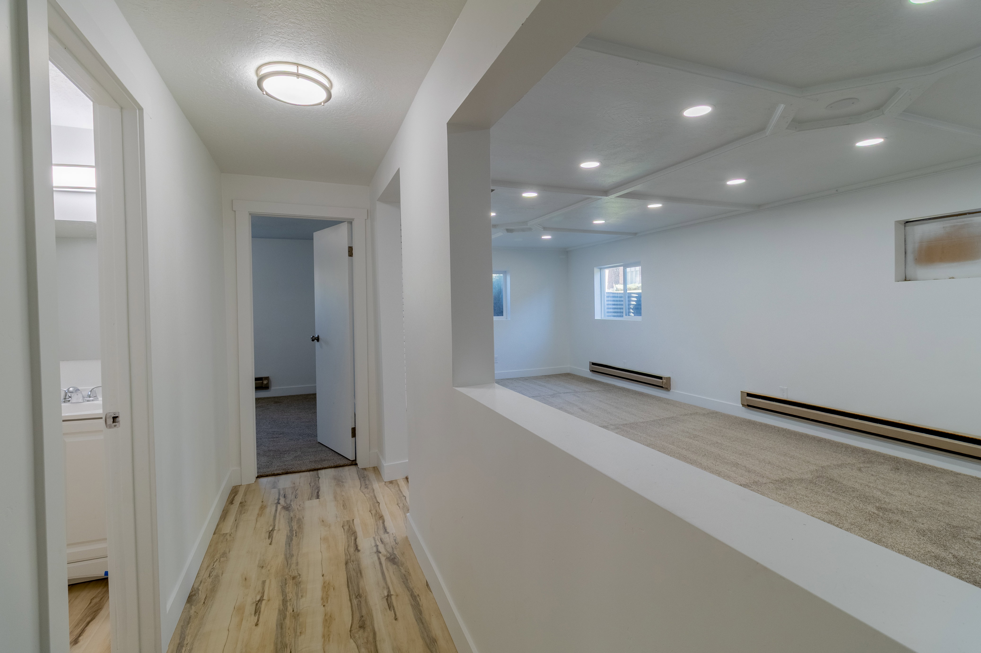 Hallway featuring wood-finish flooring, a flush-mount ceiling light, and white walls
