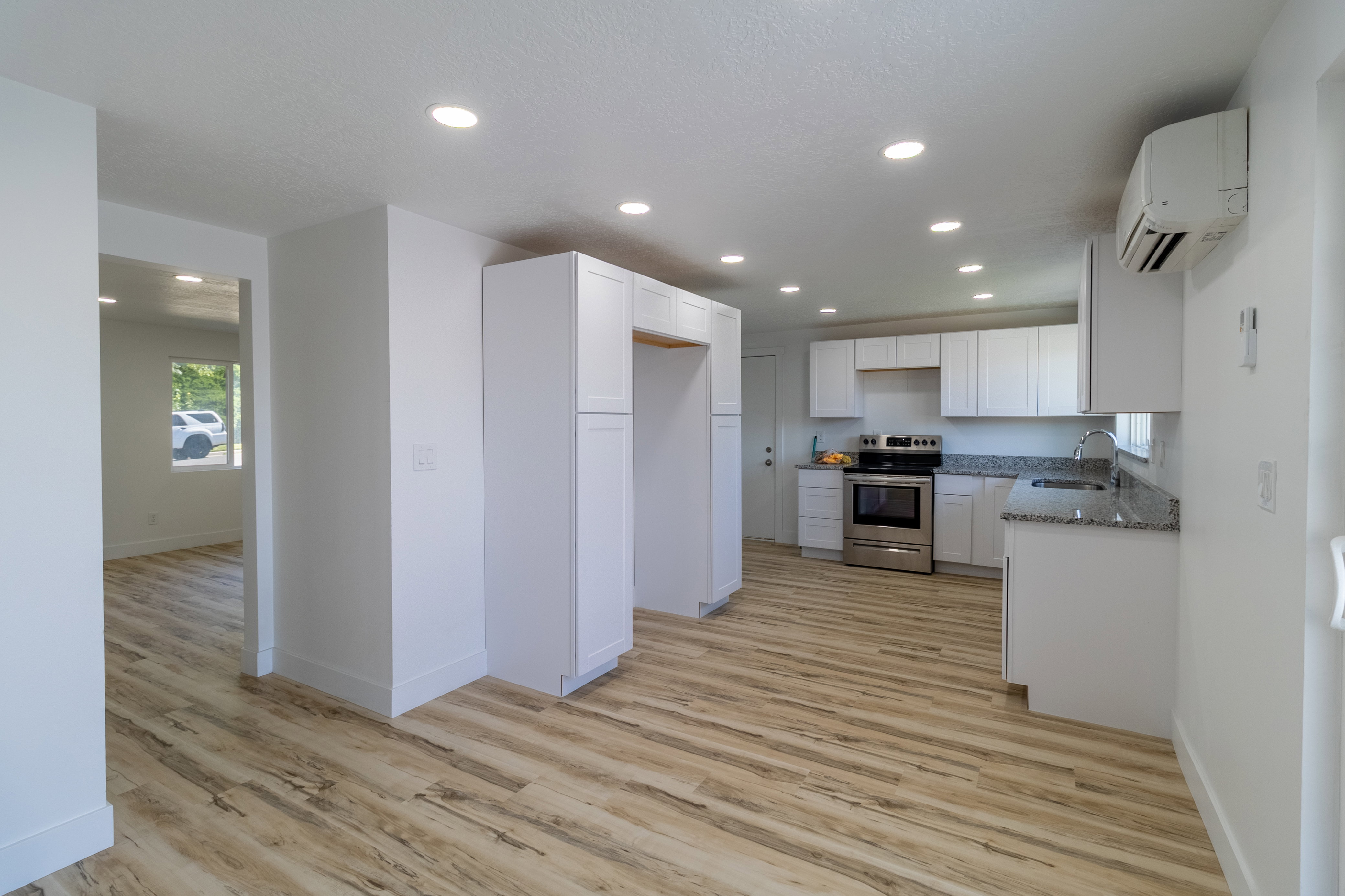 Contemporary kitchen featuring white cabinetry, granite countertops, and stainless steel range
